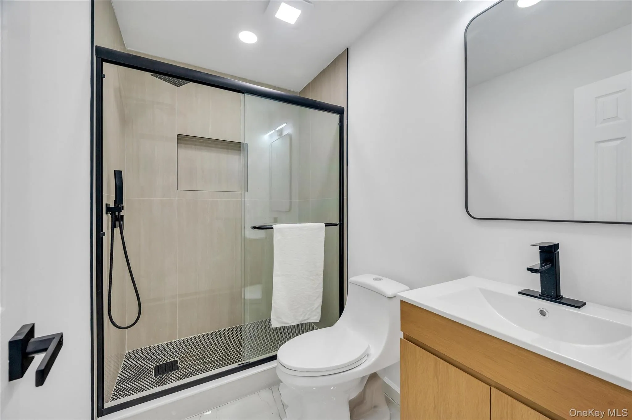 Contemporary bathroom featuring a walk-in shower with black-framed glass enclosure, built-in shower niche, and matte black fixtures Contemporary bathroom featuring a walk-in shower with black-framed glass enclosure, built-in shower niche, and matte black fixtures