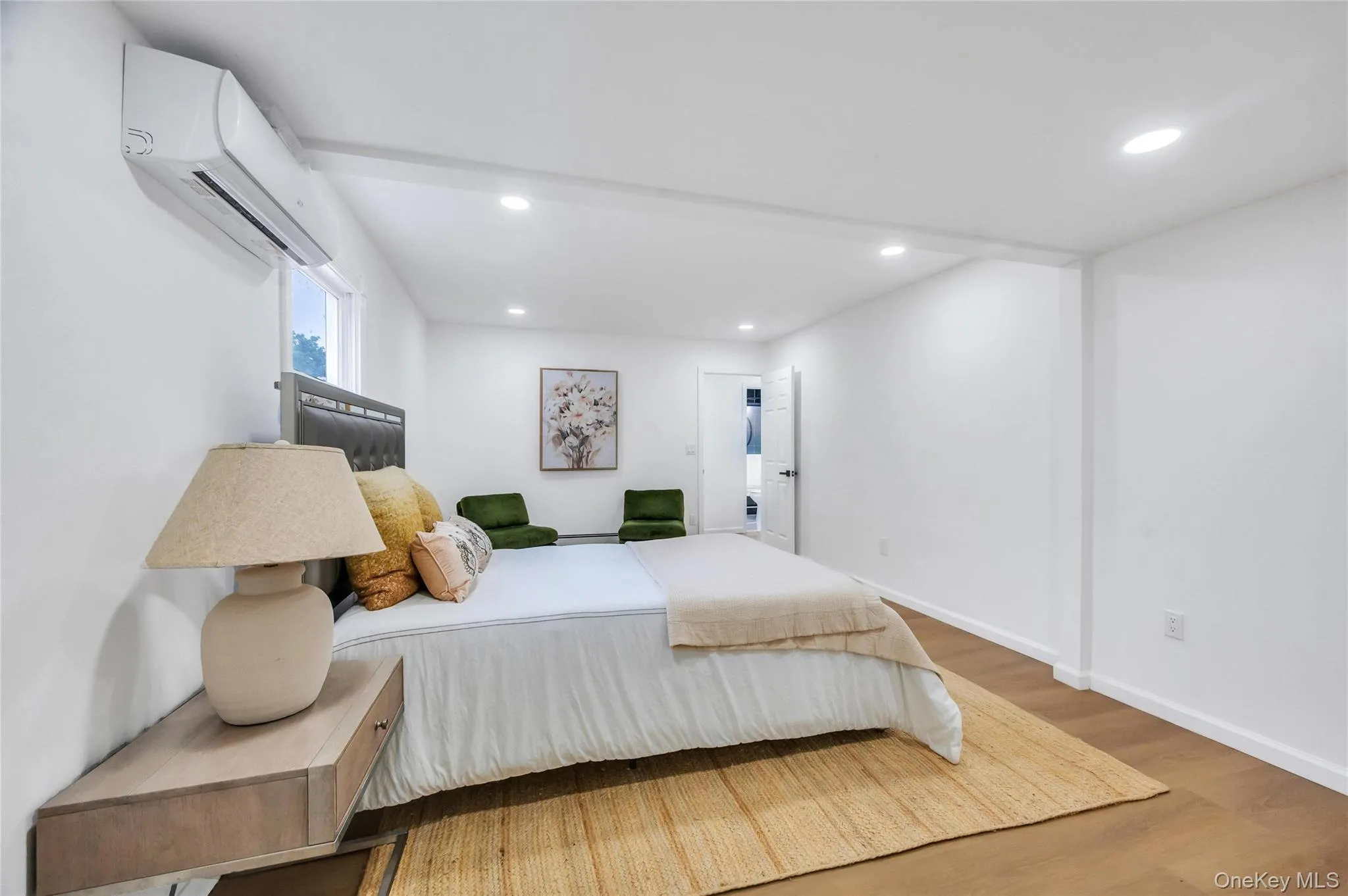 Interior room featuring warm wood-finish flooring, recessed lighting, and a wall-mounted ductless mini-split system Interior room featuring warm wood-finish flooring, recessed lighting, and a wall-mounted ductless mini-split system