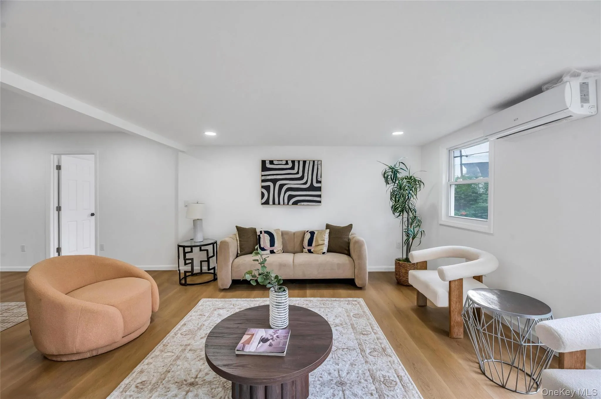 Spacious living area featuring wood-finish flooring, recessed lighting, and a window providing natural light Spacious living area featuring wood-finish flooring, recessed lighting, and a window providing natural light