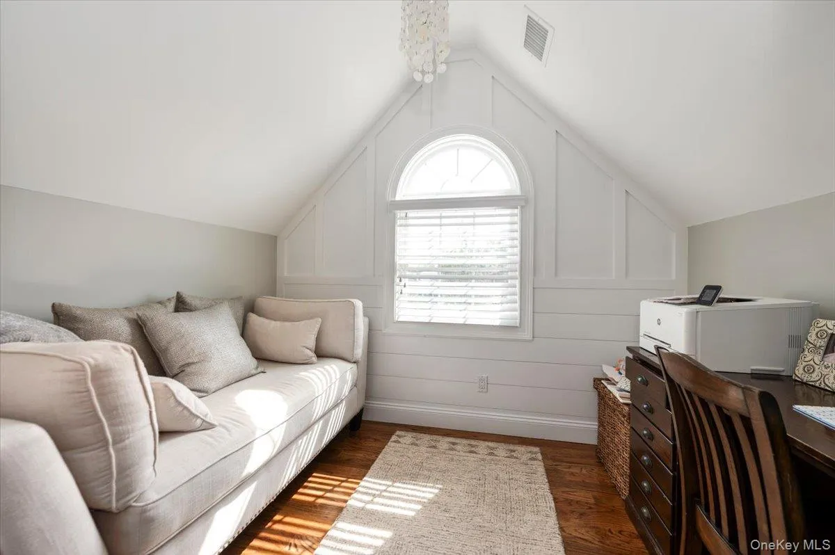 Hardwood flooring throughout this versatile space featuring an arched window, white shiplap, and a tray ceiling Hardwood flooring throughout this versatile space featuring an arched window, white shiplap, and a tray ceiling