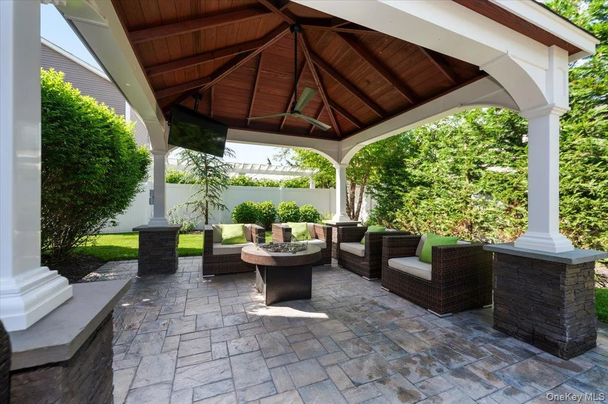 Covered outdoor patio featuring stamped concrete flooring, a detailed wood-paneled ceiling, and a built-in ceiling fan Covered outdoor patio featuring stamped concrete flooring, a detailed wood-paneled ceiling, and a built-in ceiling fan