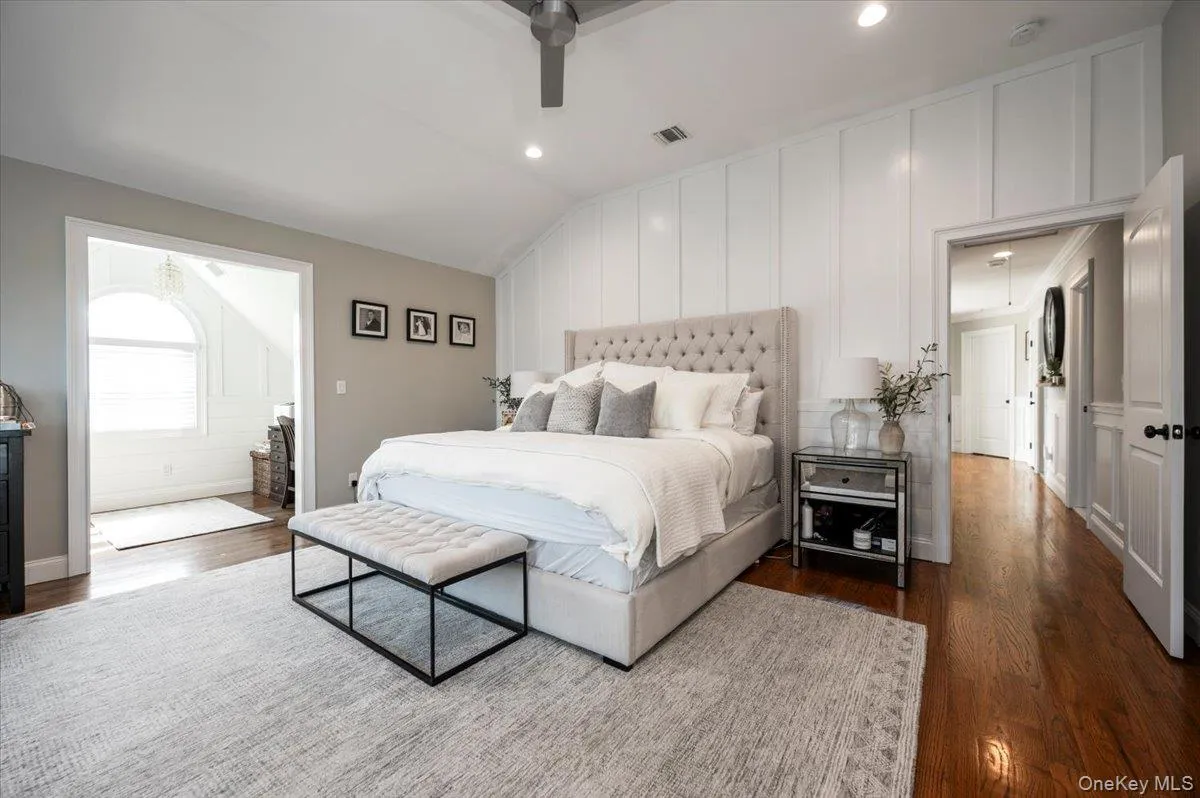 Vaulted ceiling bedroom featuring plank accent wall, recessed lighting, ceiling fan, and rich wood-finish flooring Vaulted ceiling bedroom featuring plank accent wall, recessed lighting, ceiling fan, and rich wood-finish flooring