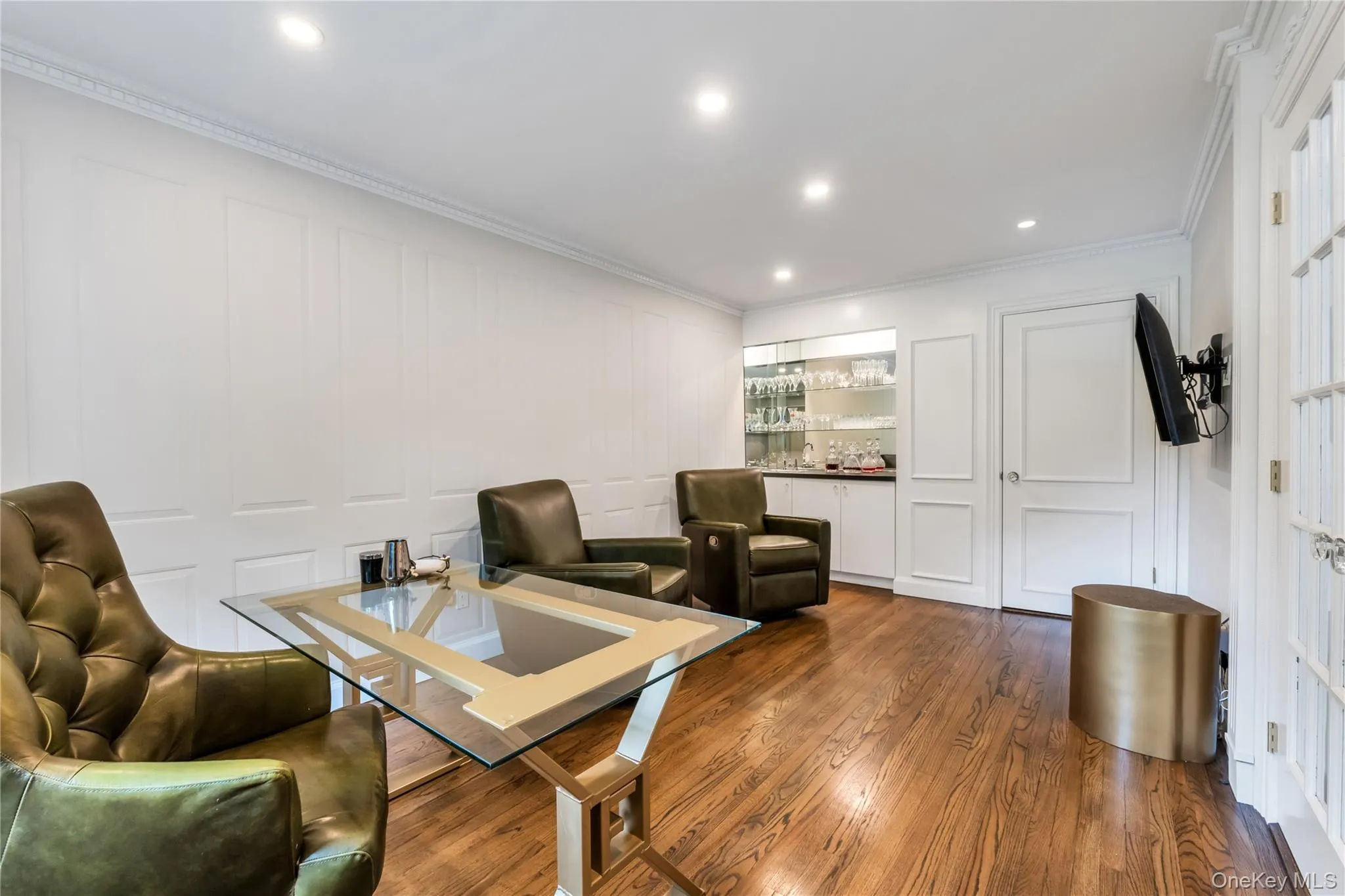 Living room with a decorative wall, ornamental molding, a bar, dark wood finished floors, and recessed lighting Living room with a decorative wall, ornamental molding, a bar, dark wood finished floors, and recessed lighting