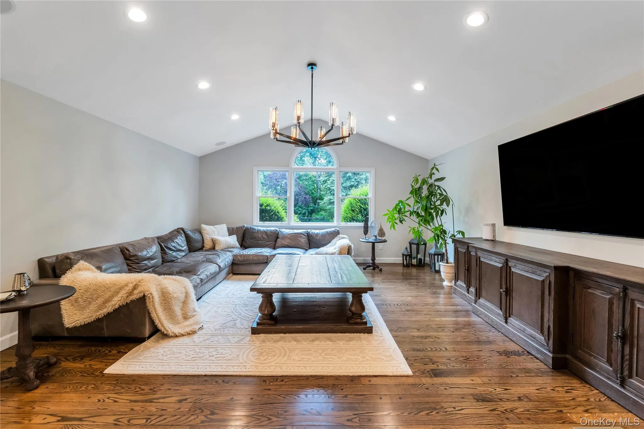 Living room featuring dark wood-style floors, a chandelier, lofted ceiling, recessed lighting, and baseboards Living room featuring dark wood-style floors, a chandelier, lofted ceiling, recessed lighting, and baseboards