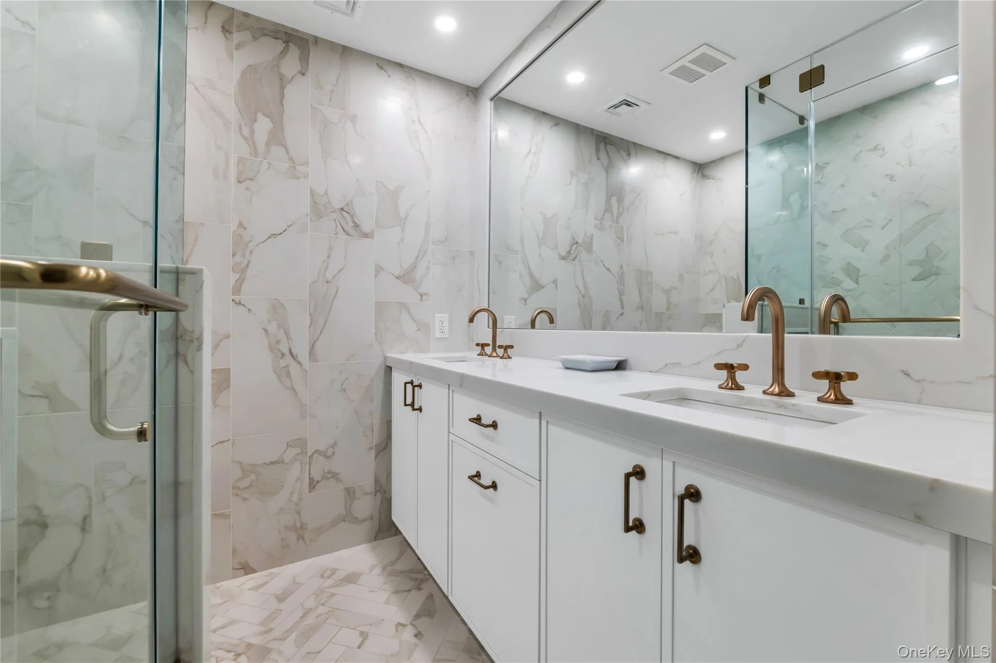 Full bathroom featuring double vanity, a marble finish shower, tile walls, marble radiant heat floors, and recessed lighting Full bathroom featuring double vanity, a marble finish shower, tile walls, marble radiant heat floors, and recessed lighting