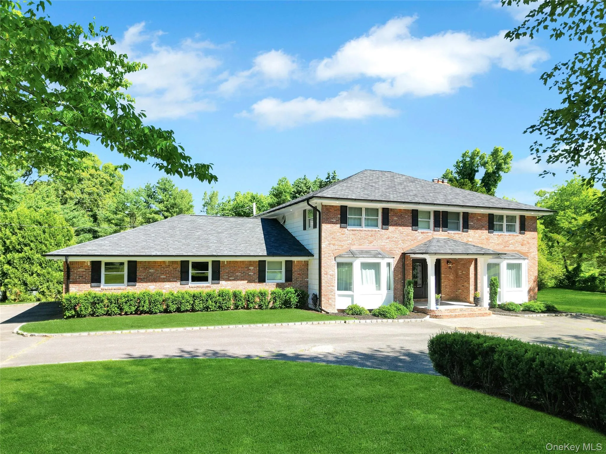 View of front of property featuring a front lawn, brick siding, and driveway View of front of property featuring a front lawn, brick siding, and driveway