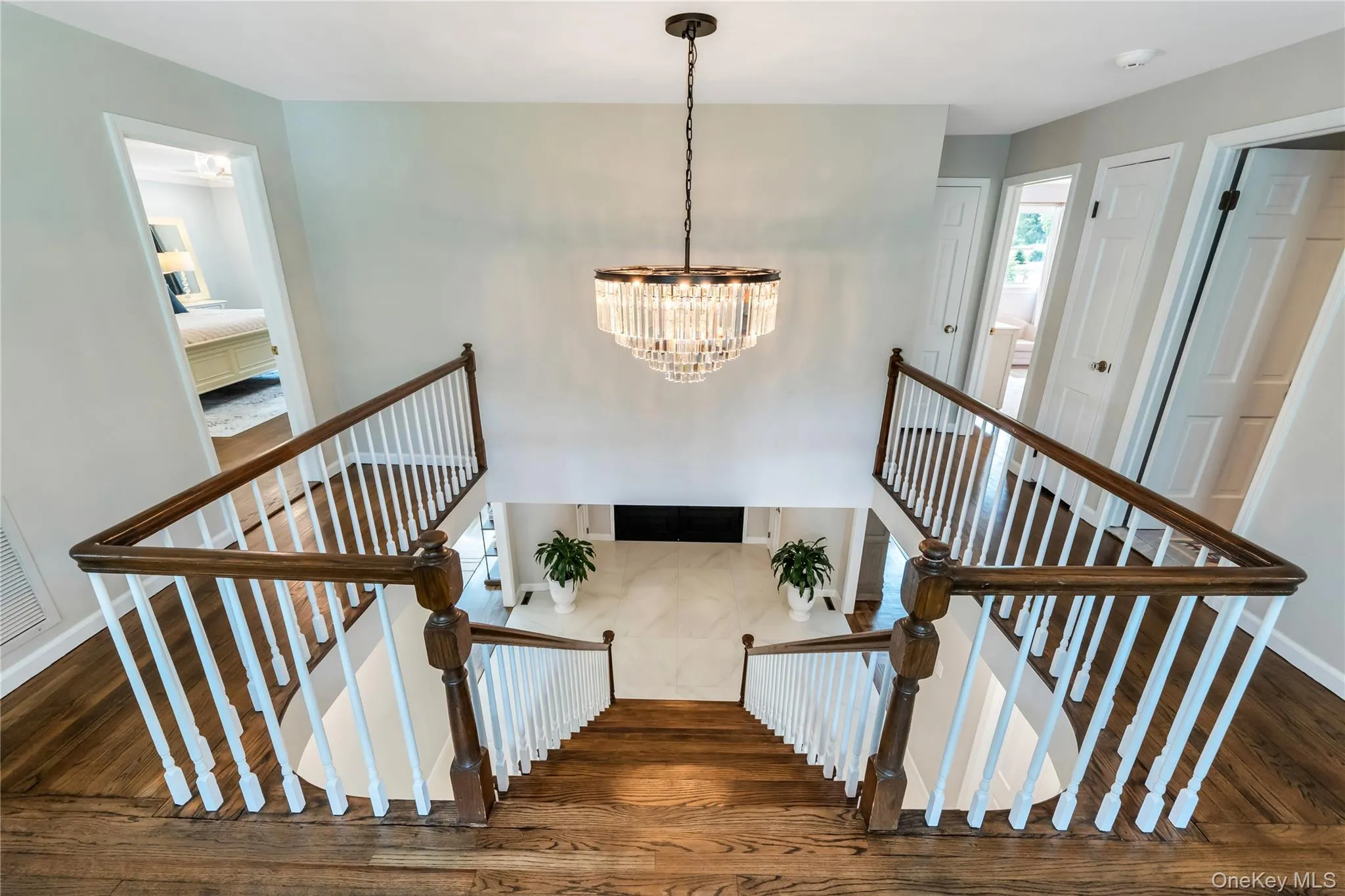 Stairway with wood finished floors, a chandelier, and baseboards Stairway with wood finished floors, a chandelier, and baseboards
