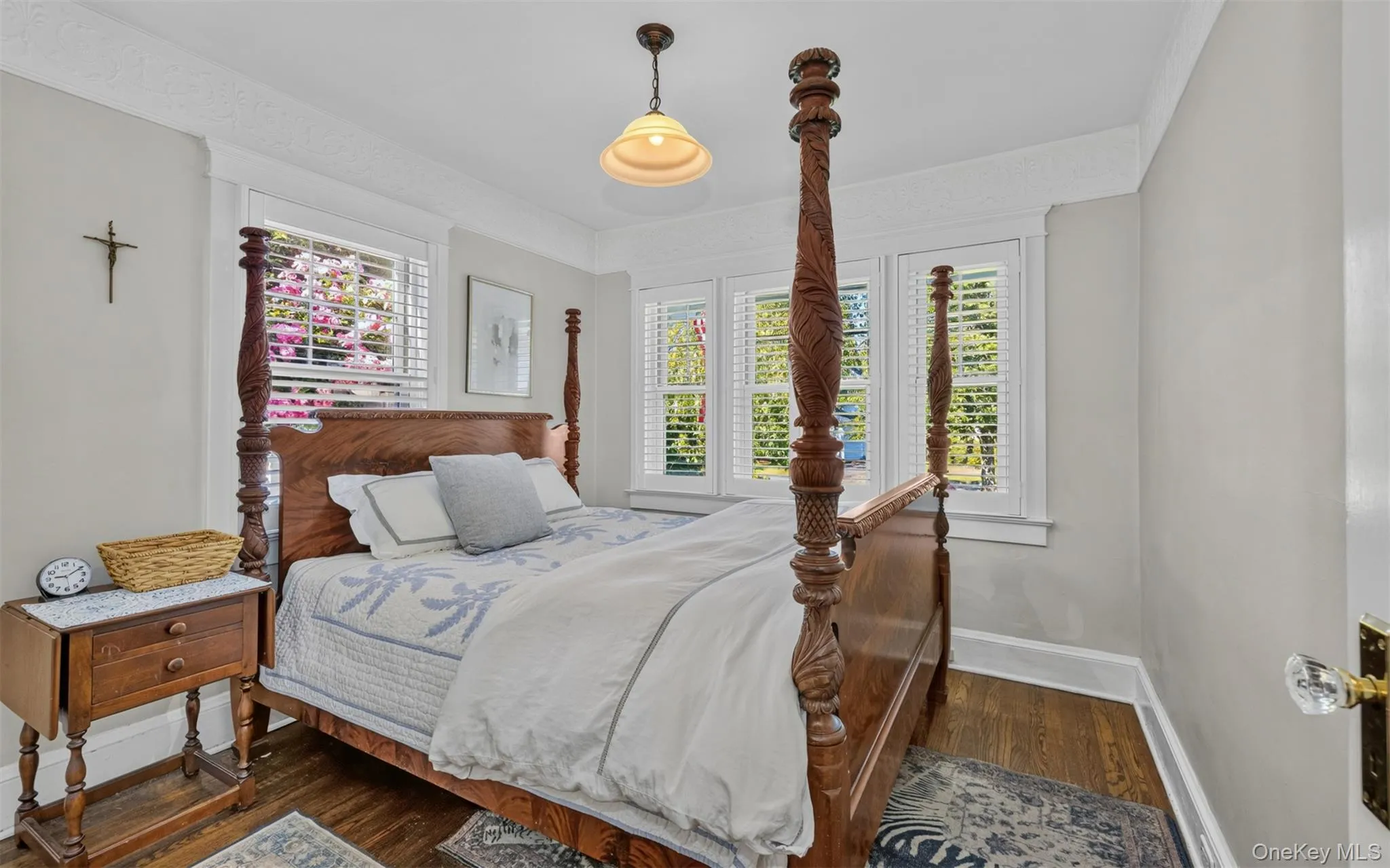 First floor primary bedroom featuring plantation shutters, crown molding and hardwood floors First floor primary bedroom featuring plantation shutters, crown molding and hardwood floors