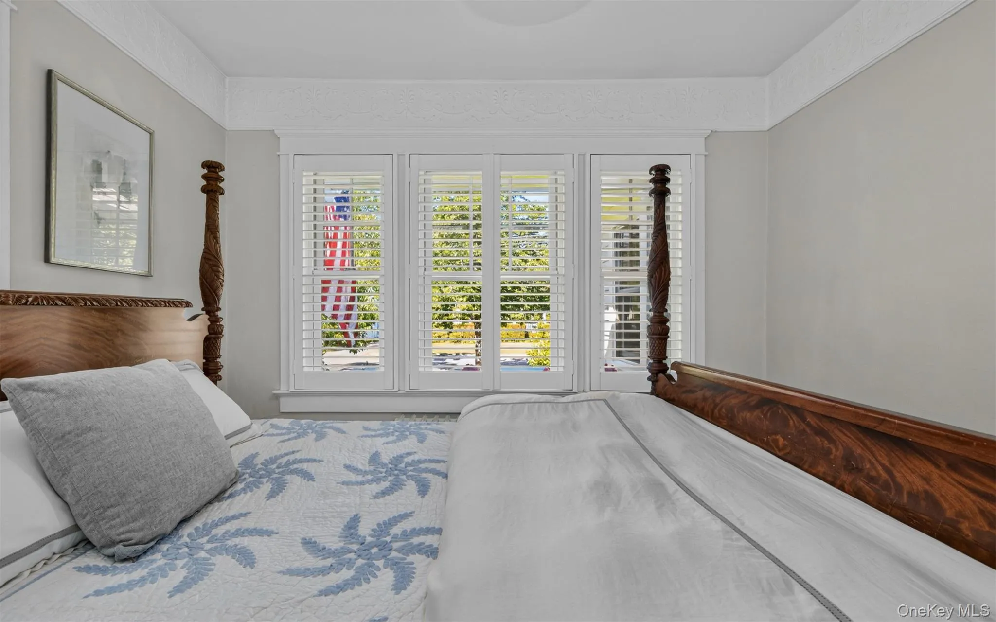 First floor primary bedroom featuring plantation shutters, crown molding and hardwood floors First floor primary bedroom featuring plantation shutters, crown molding and hardwood floors