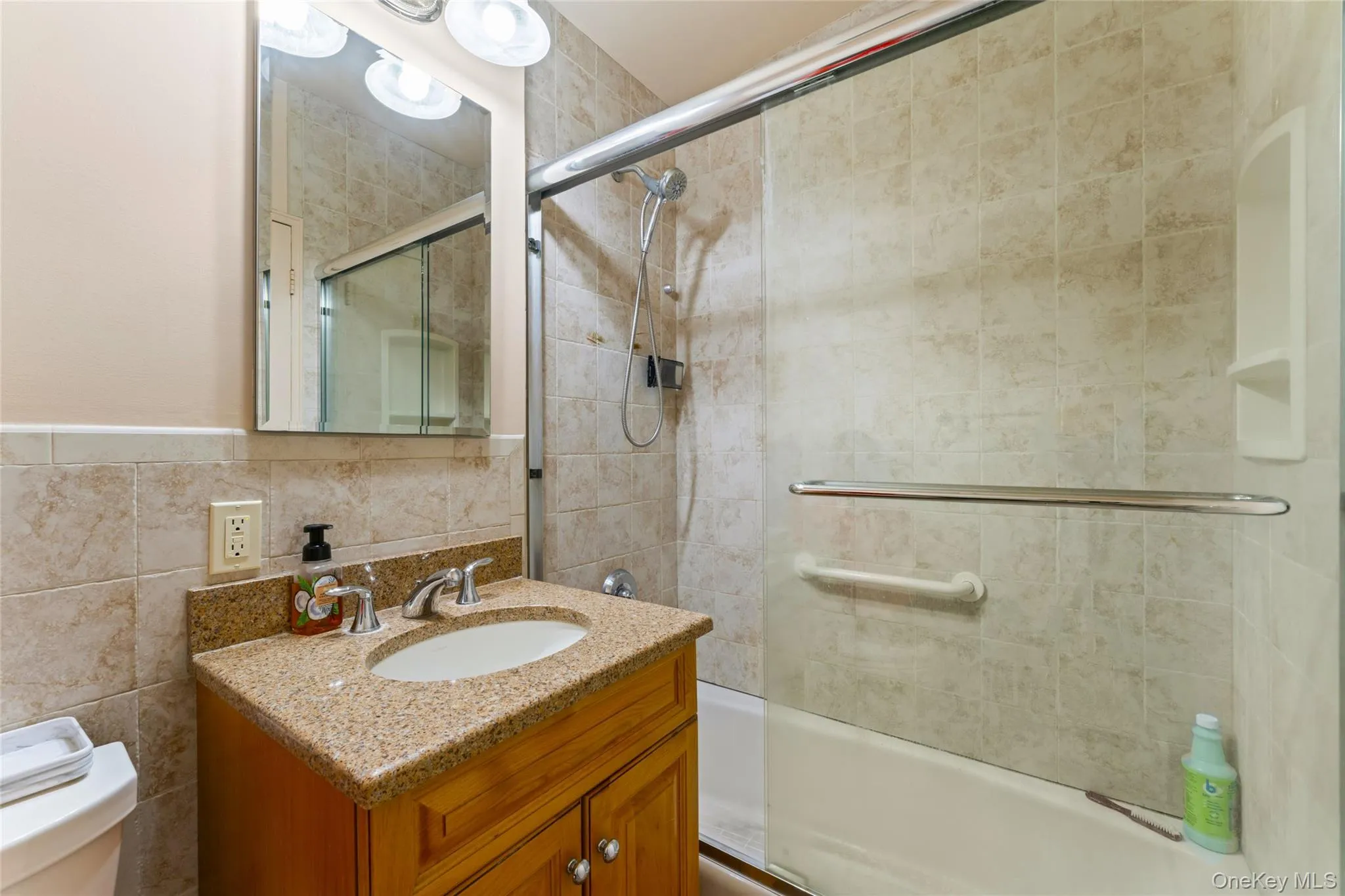 Bathroom featuring a wood vanity with a stone countertop, an oval undermount sink, and a chrome faucet Bathroom featuring a wood vanity with a stone countertop, an oval undermount sink, and a chrome faucet