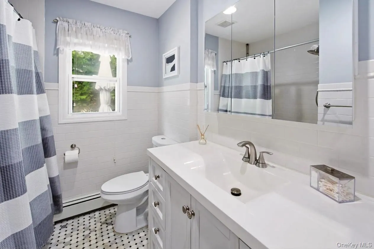 Tastefully designed bathroom featuring a white vanity with integrated sink, brushed nickel faucet, and custom tile flooring Tastefully designed bathroom featuring a white vanity with integrated sink, brushed nickel faucet, and custom tile flooring