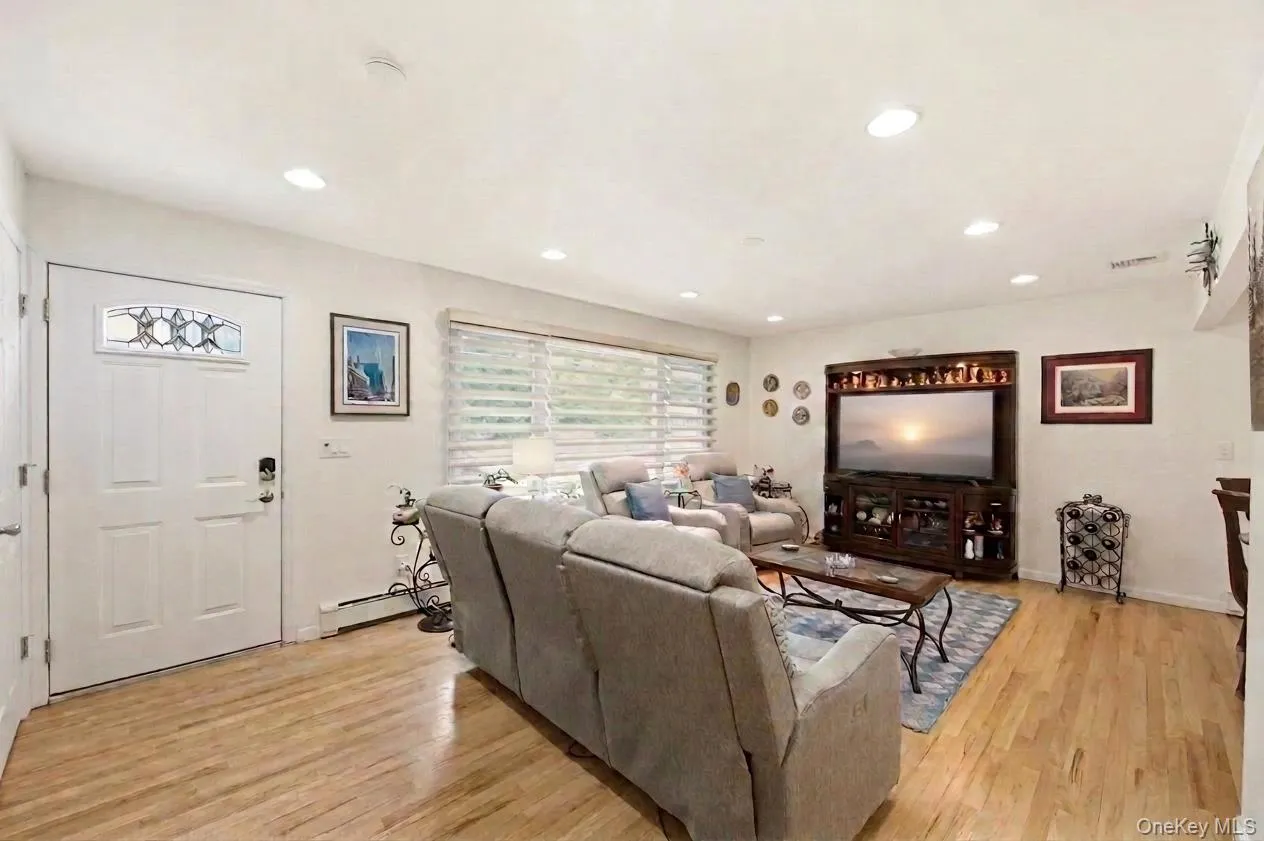 Sun-drenched living area featuring wood-finish flooring, recessed lighting, and front entry with oversized windows. Sun-drenched living area featuring wood-finish flooring, recessed lighting, and front entry with oversized windows.