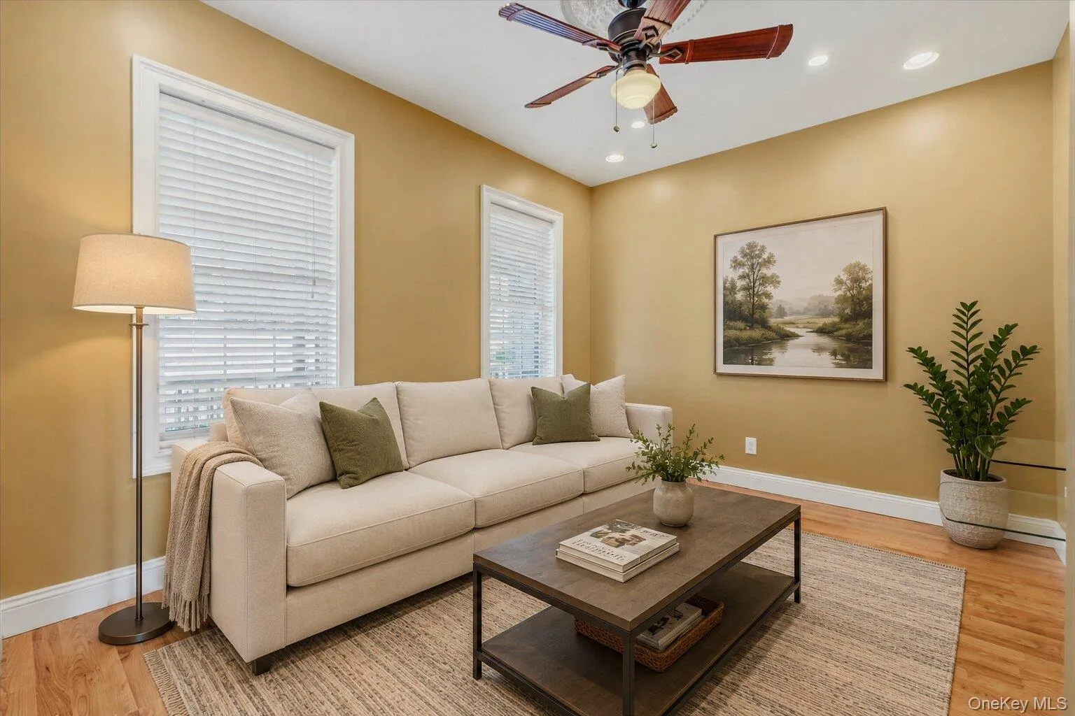 Virtually Staged. Bright living room with hardwood flooring, high ceilings, recessed lighting, ceiling fan, and large windows with white trim. The space opens nicely toward the entry hall and staircase, creating a comfortable flow through the main level. Virtually Staged. Bright living room with hardwood flooring, high ceilings, recessed lighting, ceiling fan, and large windows with white trim. The space opens nicely toward the entry hall and staircase, creating a comfortable flow through the main level.