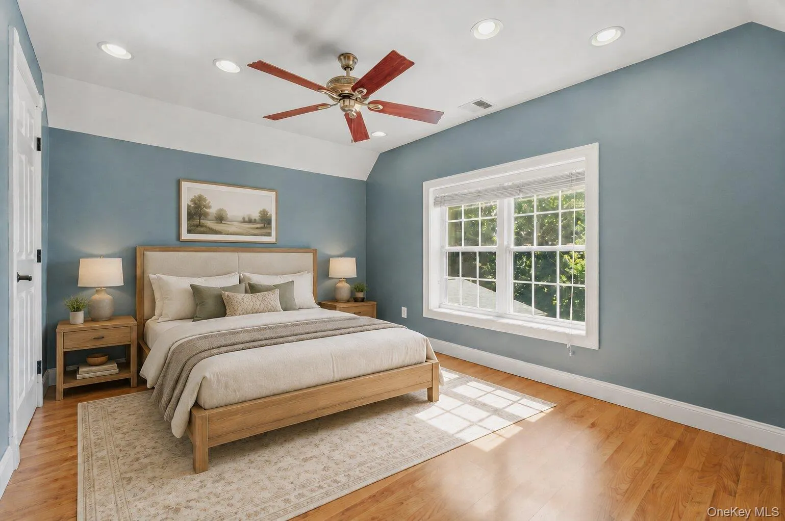 Virtually Staged. Bright bedroom featuring blue accent walls, wood-style flooring, recessed lighting, ceiling fan, white trim, and a large window with scenic water views. Virtually Staged. Bright bedroom featuring blue accent walls, wood-style flooring, recessed lighting, ceiling fan, white trim, and a large window with scenic water views.