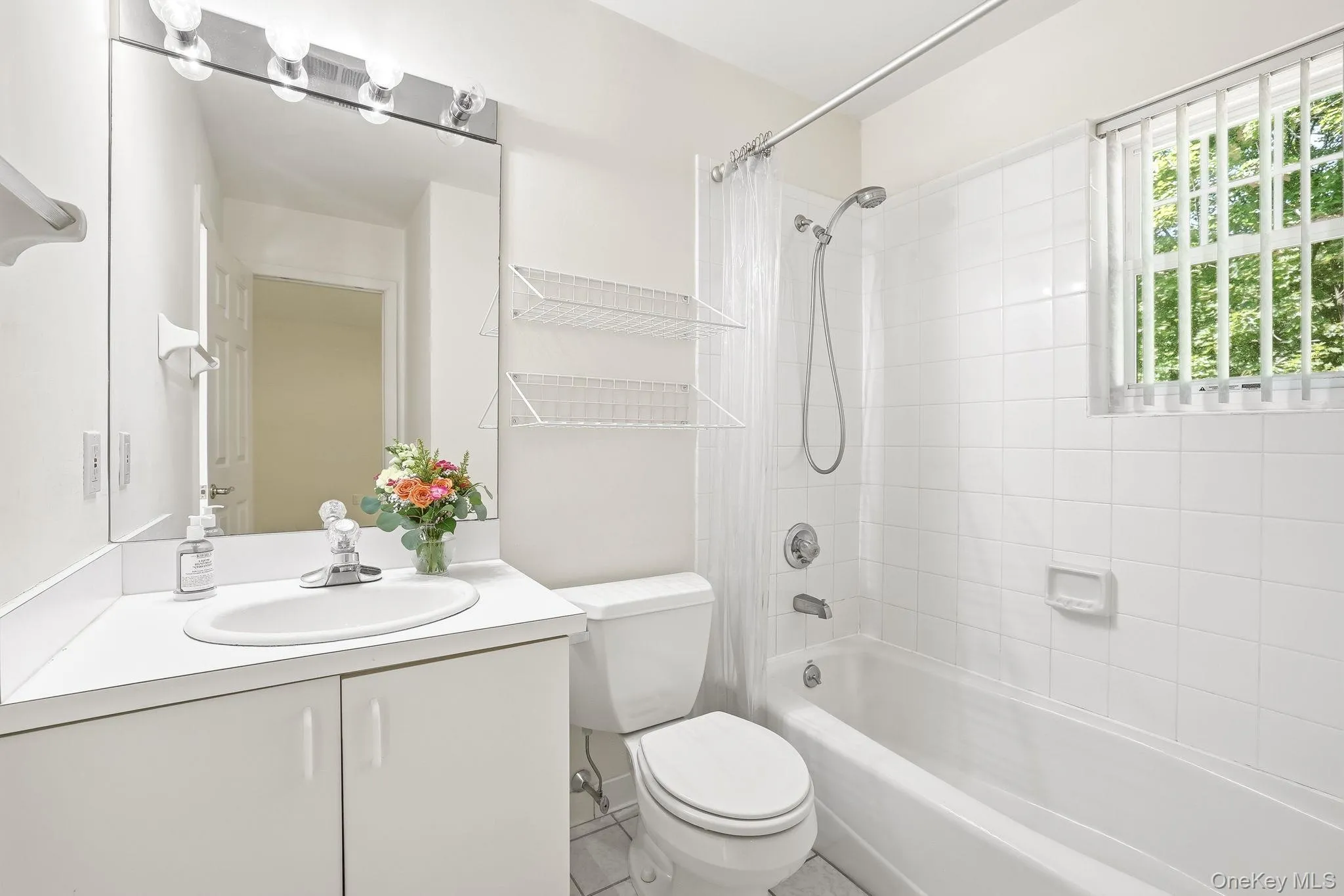 This bathroom with white ceramic tiles, and a window and a spacious vanity also opens to the sitting room This bathroom with white ceramic tiles, and a window and a spacious vanity also opens to the sitting room