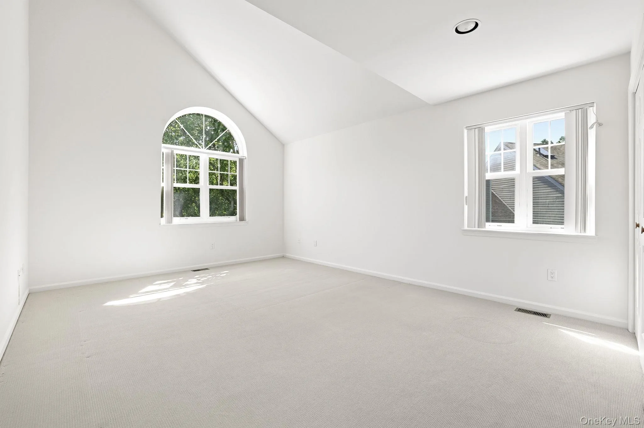 The primary bedroom has a soaring ceiling and recessed lighting and distinctive palladium window The primary bedroom has a soaring ceiling and recessed lighting and distinctive palladium window