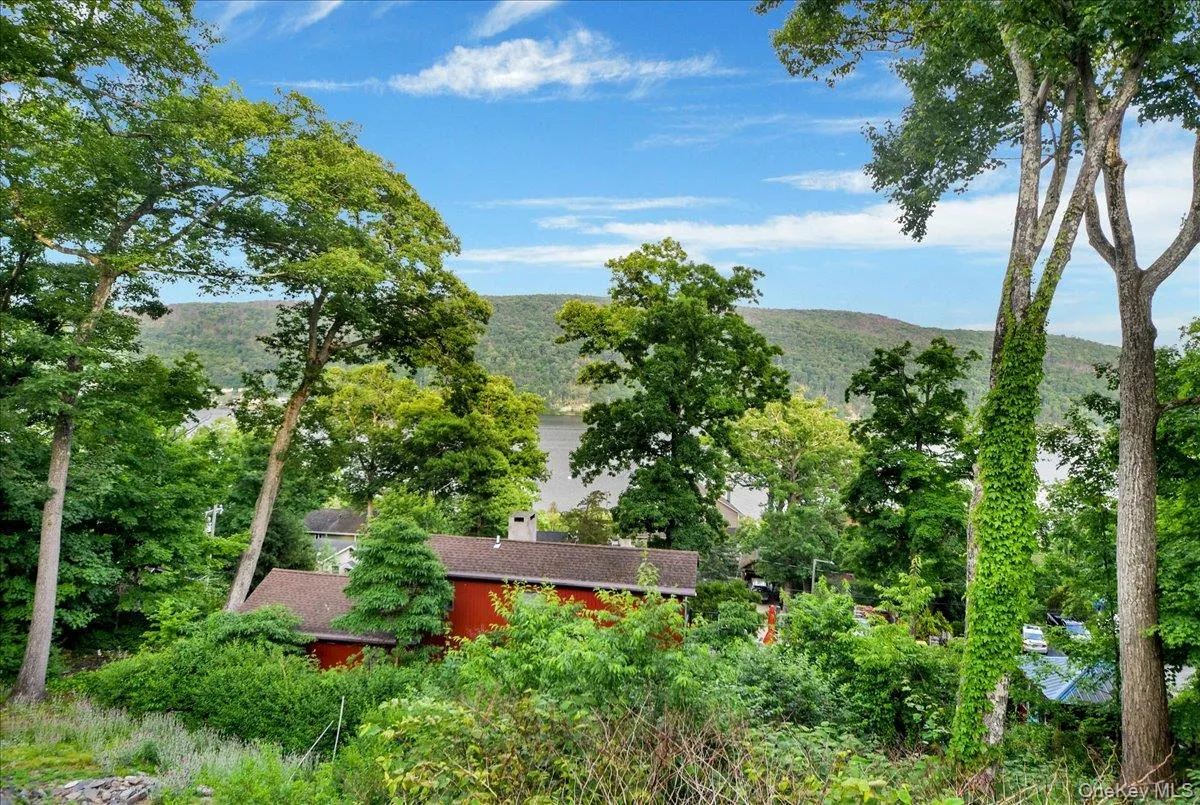 Lush, mature trees frame a tranquil water body and distant rolling hills Lush, mature trees frame a tranquil water body and distant rolling hills