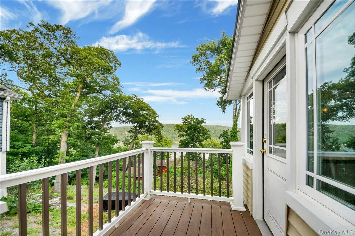 Private balcony featuring composite decking, white railings with dark balusters, and a glass-paneled entry door Private balcony featuring composite decking, white railings with dark balusters, and a glass-paneled entry door