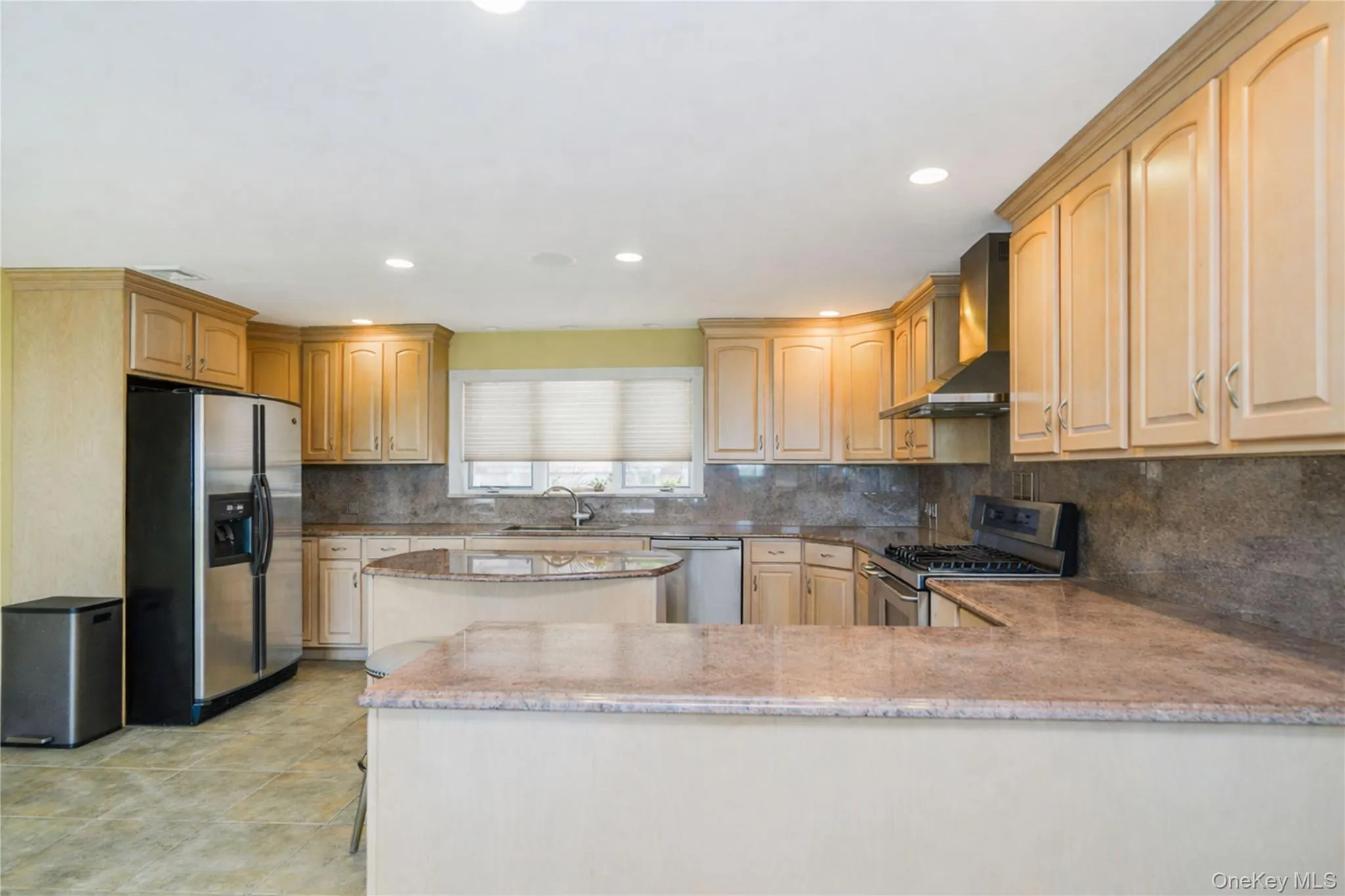 Kitchen featuring light-toned cabinetry, stainless steel appliances, and stone countertops Kitchen featuring light-toned cabinetry, stainless steel appliances, and stone countertops