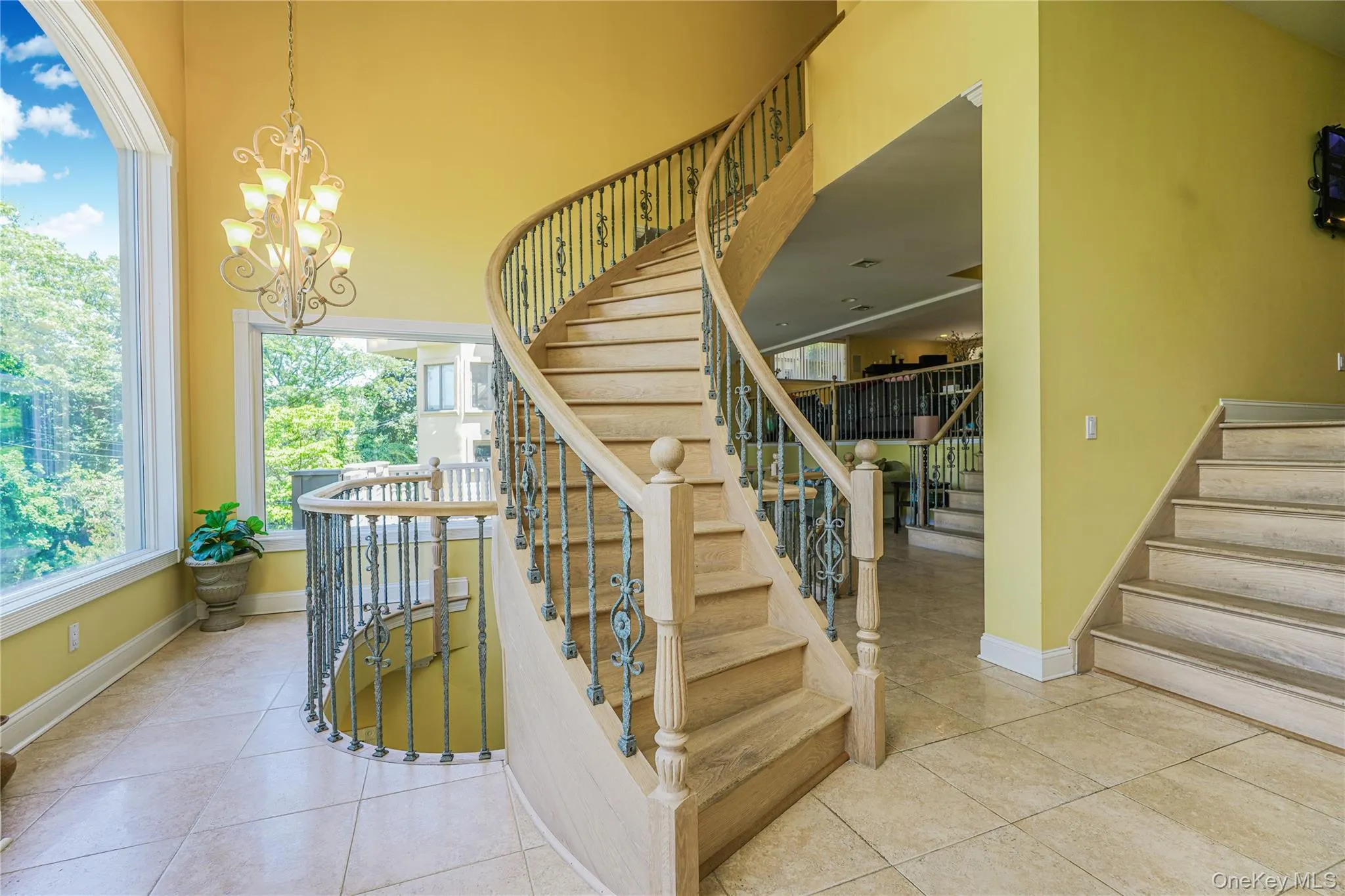 Grand curved staircase featuring wood-finish treads and an ornate metal railing Grand curved staircase featuring wood-finish treads and an ornate metal railing