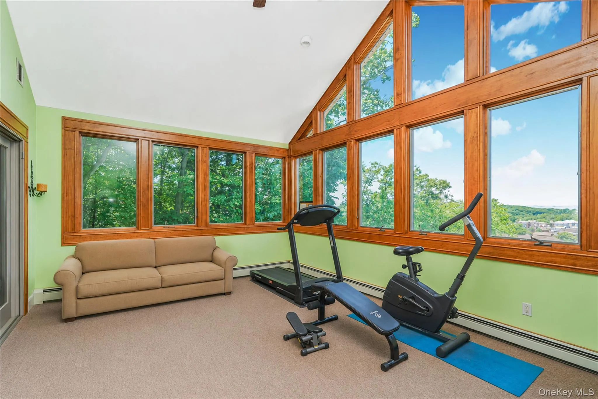 Room featuring extensive natural wood-frame windows, vaulted ceiling, and light green wall finish Room featuring extensive natural wood-frame windows, vaulted ceiling, and light green wall finish