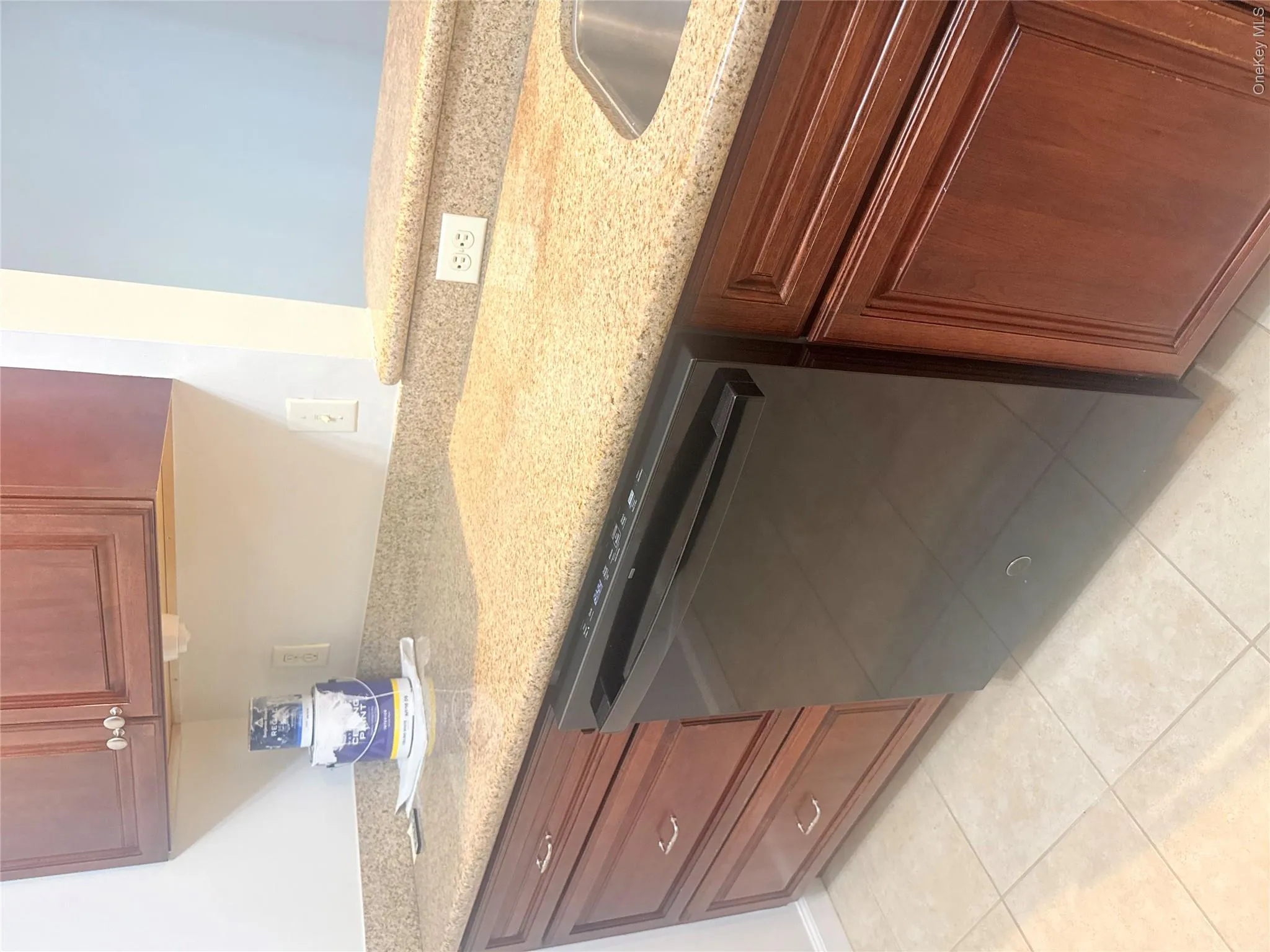 Kitchen featuring stone-finish countertops, wood cabinetry, a black dishwasher, and a stainless steel sink Kitchen featuring stone-finish countertops, wood cabinetry, a black dishwasher, and a stainless steel sink
