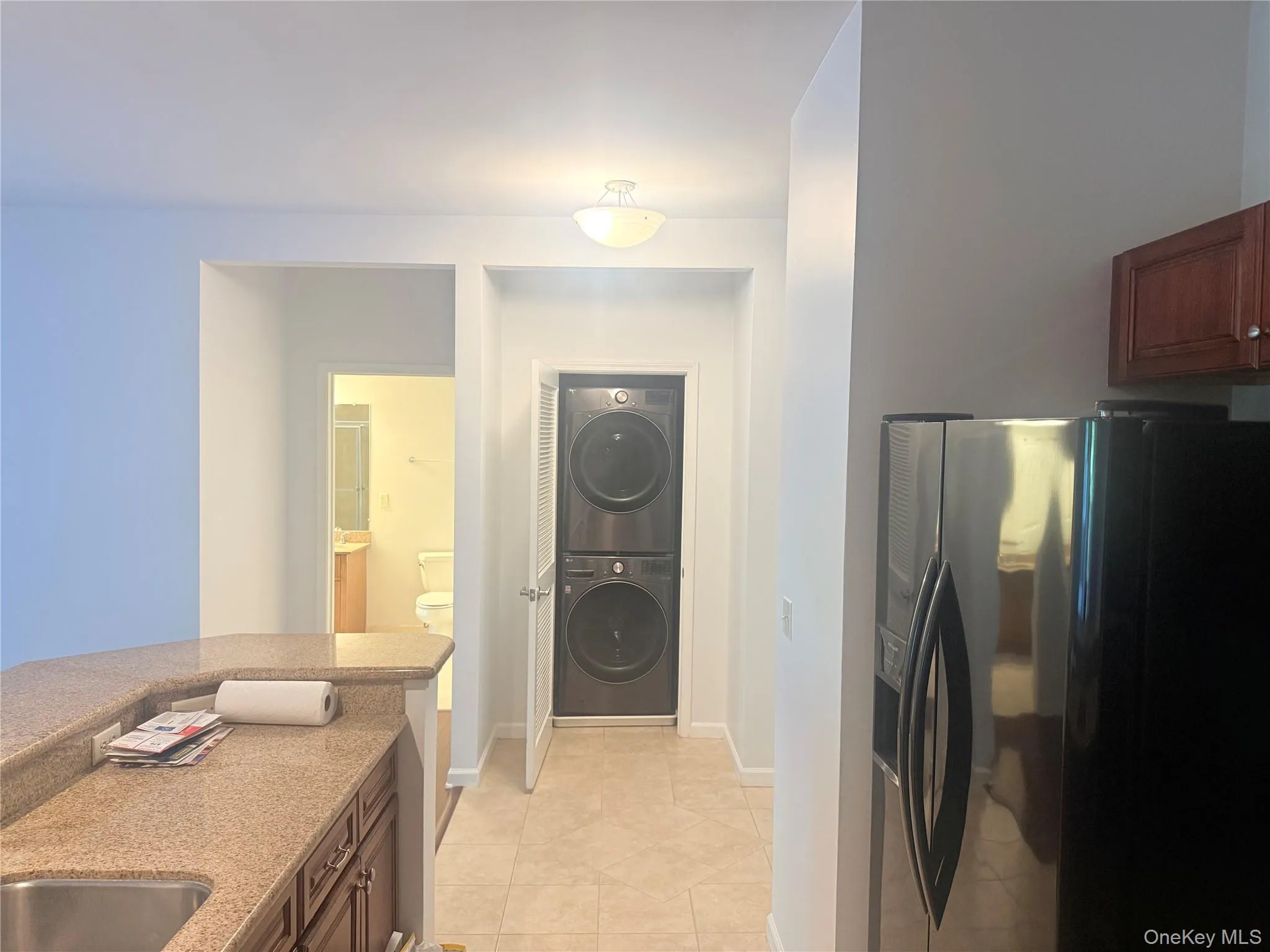 Built-in stacked washer and dryer unit, complemented by a stainless steel refrigerator and wood-finish cabinetry Built-in stacked washer and dryer unit, complemented by a stainless steel refrigerator and wood-finish cabinetry