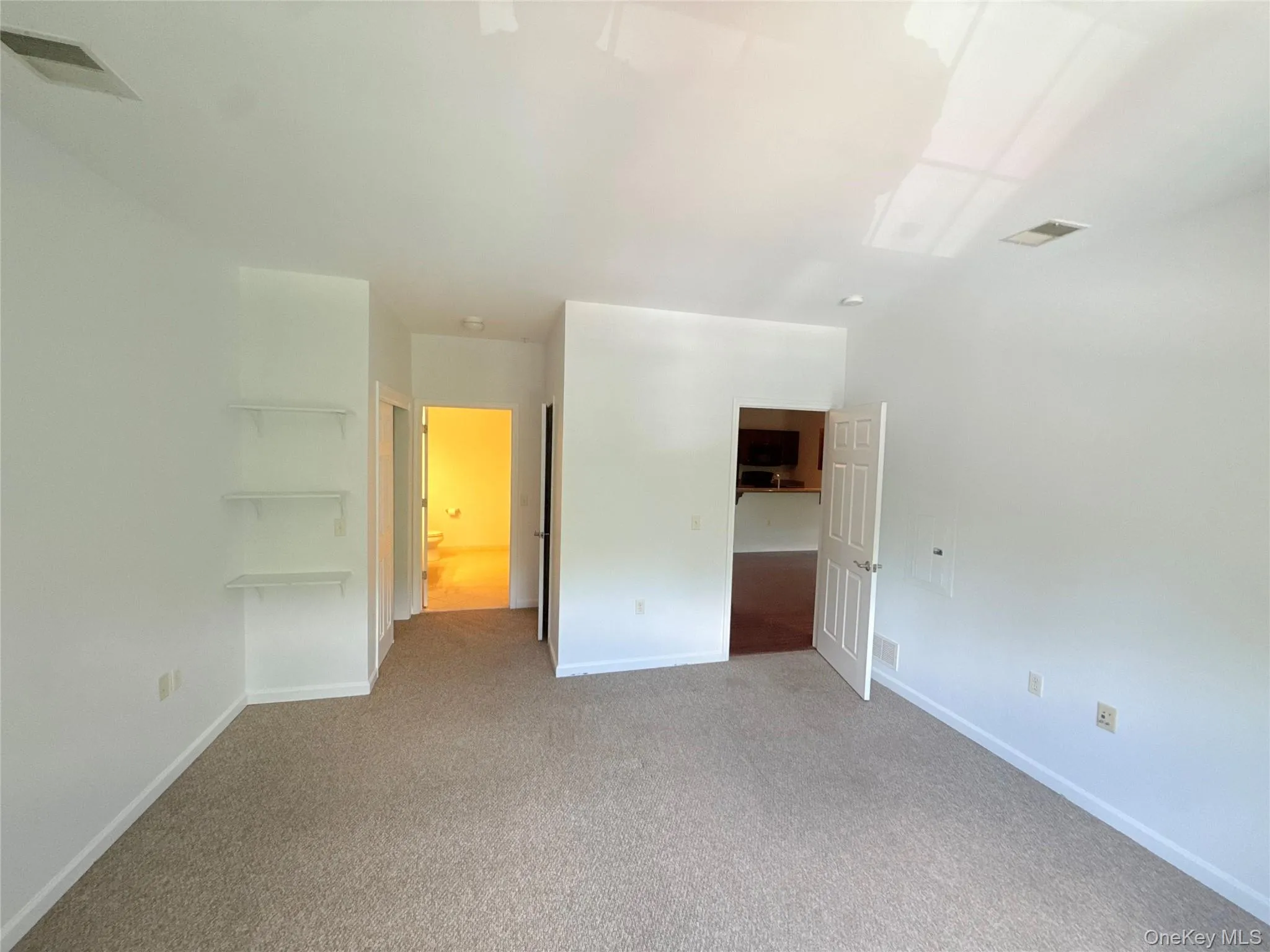Carpeted room with a neutral color palette, featuring recessed lighting and a ceiling vent Carpeted room with a neutral color palette, featuring recessed lighting and a ceiling vent