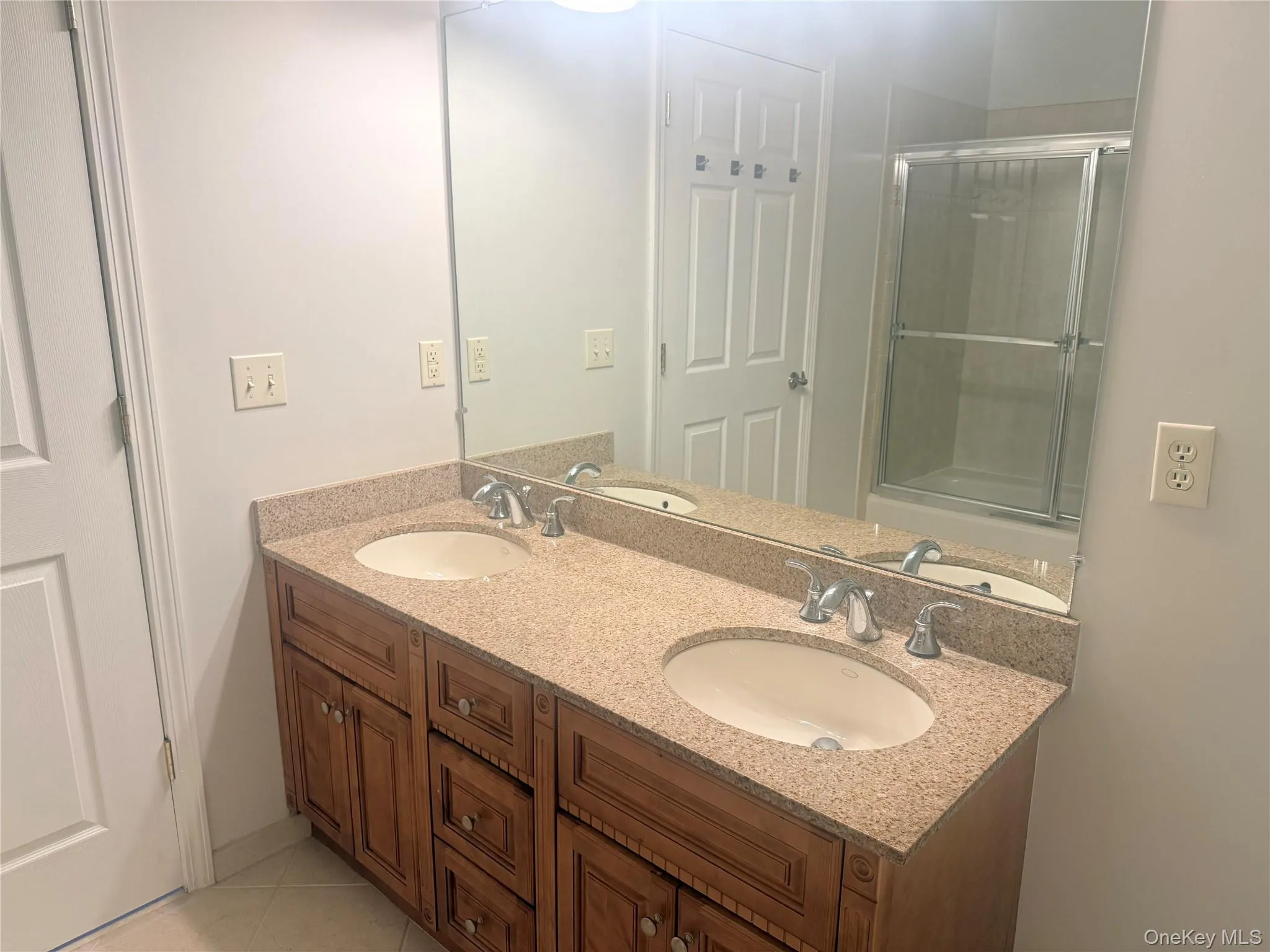Double vanity with granite-finish countertop, dual integrated sinks, and chrome fixtures Double vanity with granite-finish countertop, dual integrated sinks, and chrome fixtures