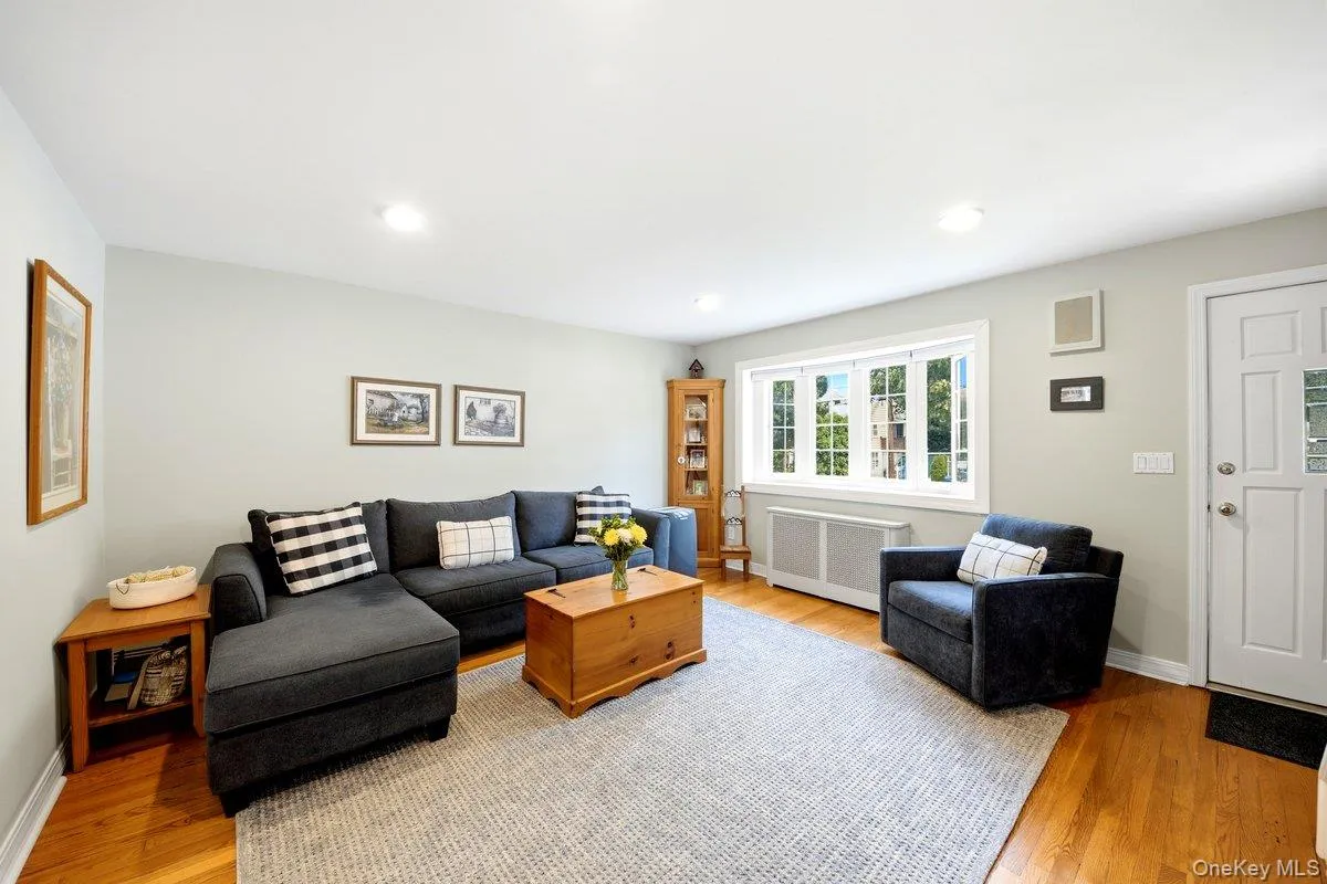 Living area featuring hardwood flooring, recessed lighting, and a multi-pane window with a radiator cover below Living area featuring hardwood flooring, recessed lighting, and a multi-pane window with a radiator cover below