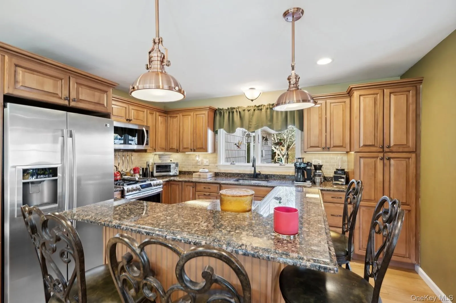 Kitchen featuring a center island, hanging light fixtures, dark stone countertops, decorative backsplash, and appliances with stainless steel finishes Kitchen featuring a center island, hanging light fixtures, dark stone countertops, decorative backsplash, and appliances with stainless steel finishes