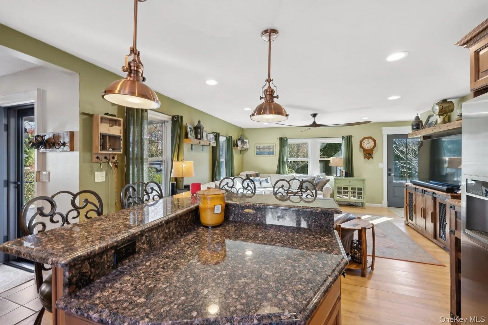 Kitchen featuring light hardwood / wood-style floors, hanging light fixtures, dark stone counters, and ceiling fan Kitchen featuring light hardwood / wood-style floors, hanging light fixtures, dark stone counters, and ceiling fan