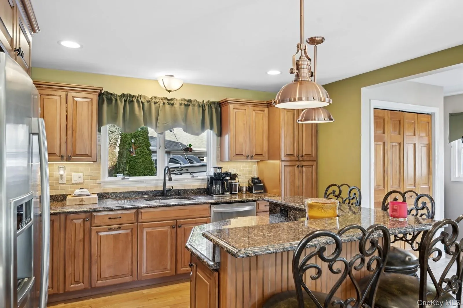 Kitchen with a kitchen breakfast bar, sink, dark stone countertops, a kitchen island, and stainless steel appliances Kitchen with a kitchen breakfast bar, sink, dark stone countertops, a kitchen island, and stainless steel appliances