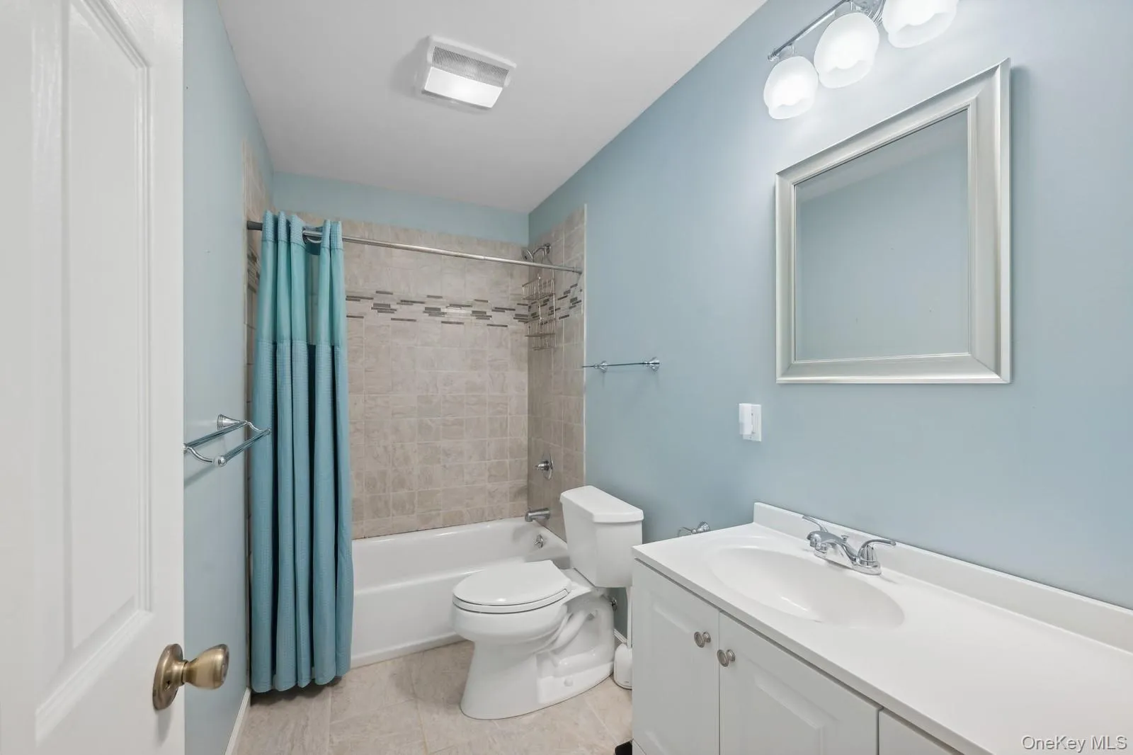Full bathroom with tile patterned flooring, shower / tub combo with curtain, vanity, and toilet Full bathroom with tile patterned flooring, shower / tub combo with curtain, vanity, and toilet