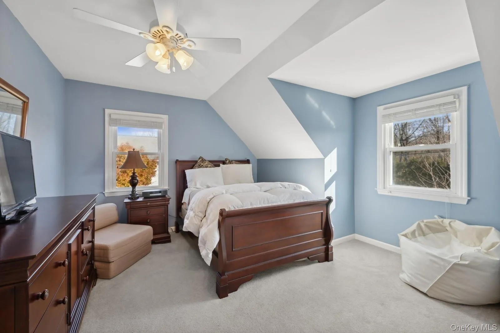 Bedroom with ceiling fan, vaulted ceiling, light carpet, and multiple windows Bedroom with ceiling fan, vaulted ceiling, light carpet, and multiple windows
