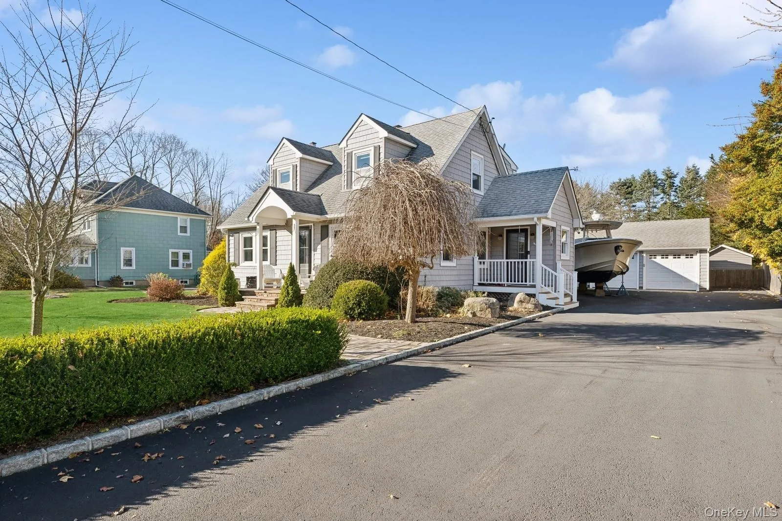 Cape cod home featuring a garage, covered porch, an outdoor structure, and a front yard Cape cod home featuring a garage, covered porch, an outdoor structure, and a front yard