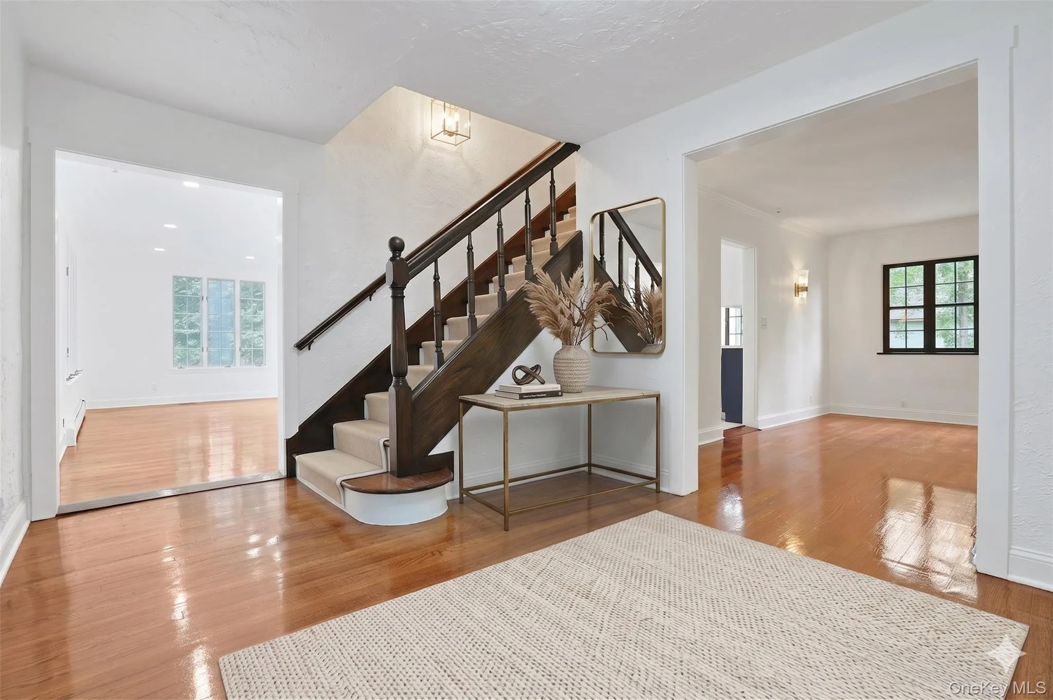 An inviting entry sets the tone for the home, where beautifully refinished hardwood floors, crisp white walls, and the original staircase showcase the perfect blend of classic Tudor character and modern updates. (Virtually Staged) An inviting entry sets the tone for the home, where beautifully refinished hardwood floors, crisp white walls, and the original staircase showcase the perfect blend of classic Tudor character and modern updates. (Virtually Staged)