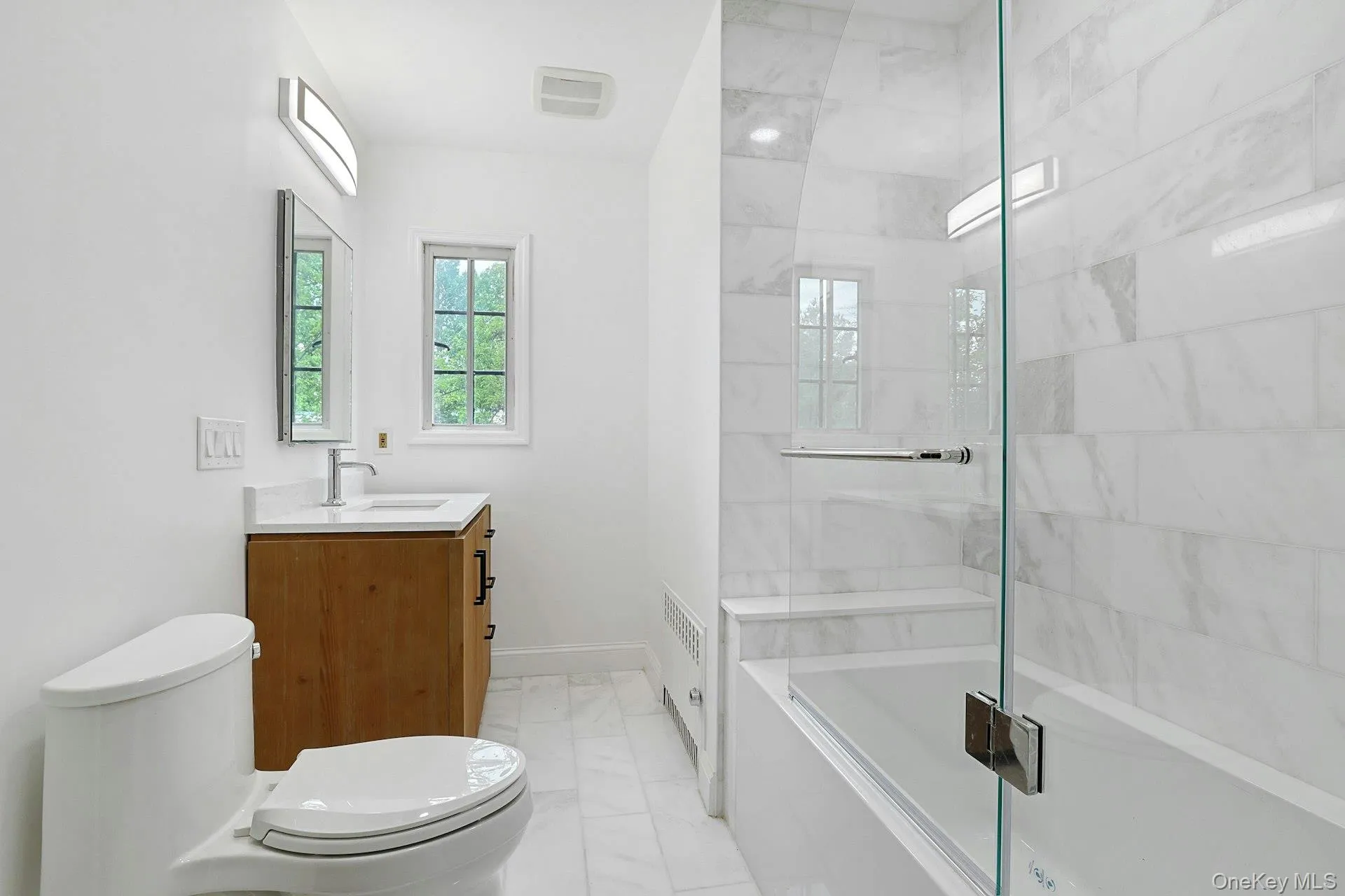 Beautifully renovated with timeless marble finishes, the hall bath features a sleek glass-enclosed tub and shower, custom vanity, and sophisticated fixtures, offering both style and comfort for family and guests. Beautifully renovated with timeless marble finishes, the hall bath features a sleek glass-enclosed tub and shower, custom vanity, and sophisticated fixtures, offering both style and comfort for family and guests.