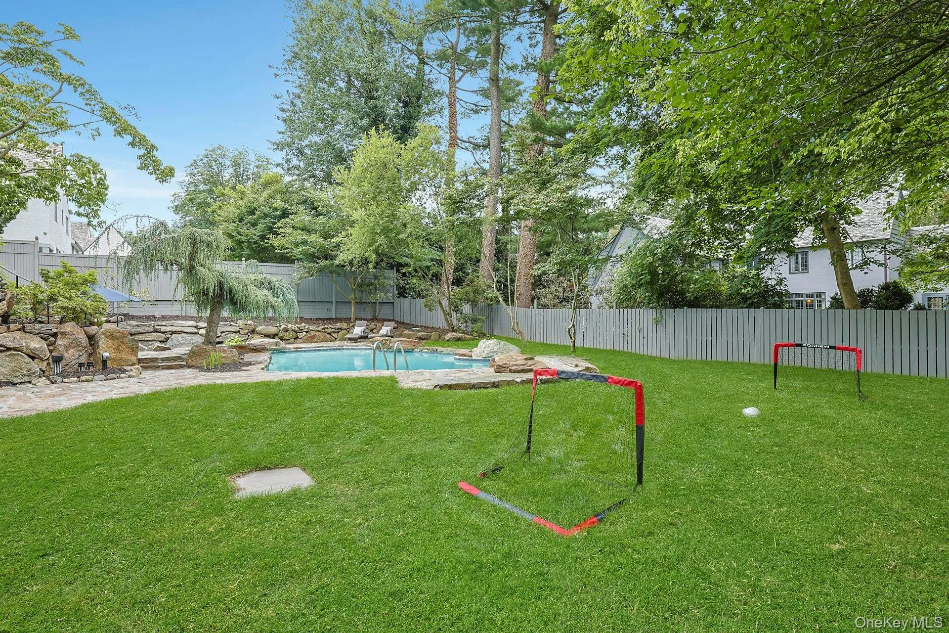 Beyond the pool, an expansive level lawn provides exceptional space for play, sports, and outdoor recreation, all surrounded by mature trees and lush landscaping that create a private backyard oasis. Beyond the pool, an expansive level lawn provides exceptional space for play, sports, and outdoor recreation, all surrounded by mature trees and lush landscaping that create a private backyard oasis.