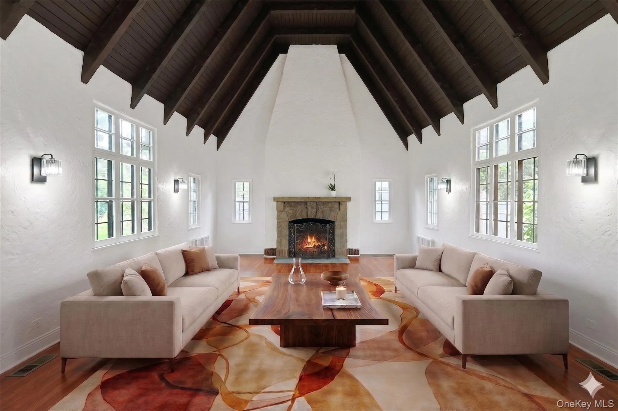 The breathtaking living room is the heart of the home, featuring soaring cathedral ceilings, dramatic exposed beams, oversized windows, and a stunning wood-burning fireplace with stone surround. (Virtually Staged) The breathtaking living room is the heart of the home, featuring soaring cathedral ceilings, dramatic exposed beams, oversized windows, and a stunning wood-burning fireplace with stone surround. (Virtually Staged)