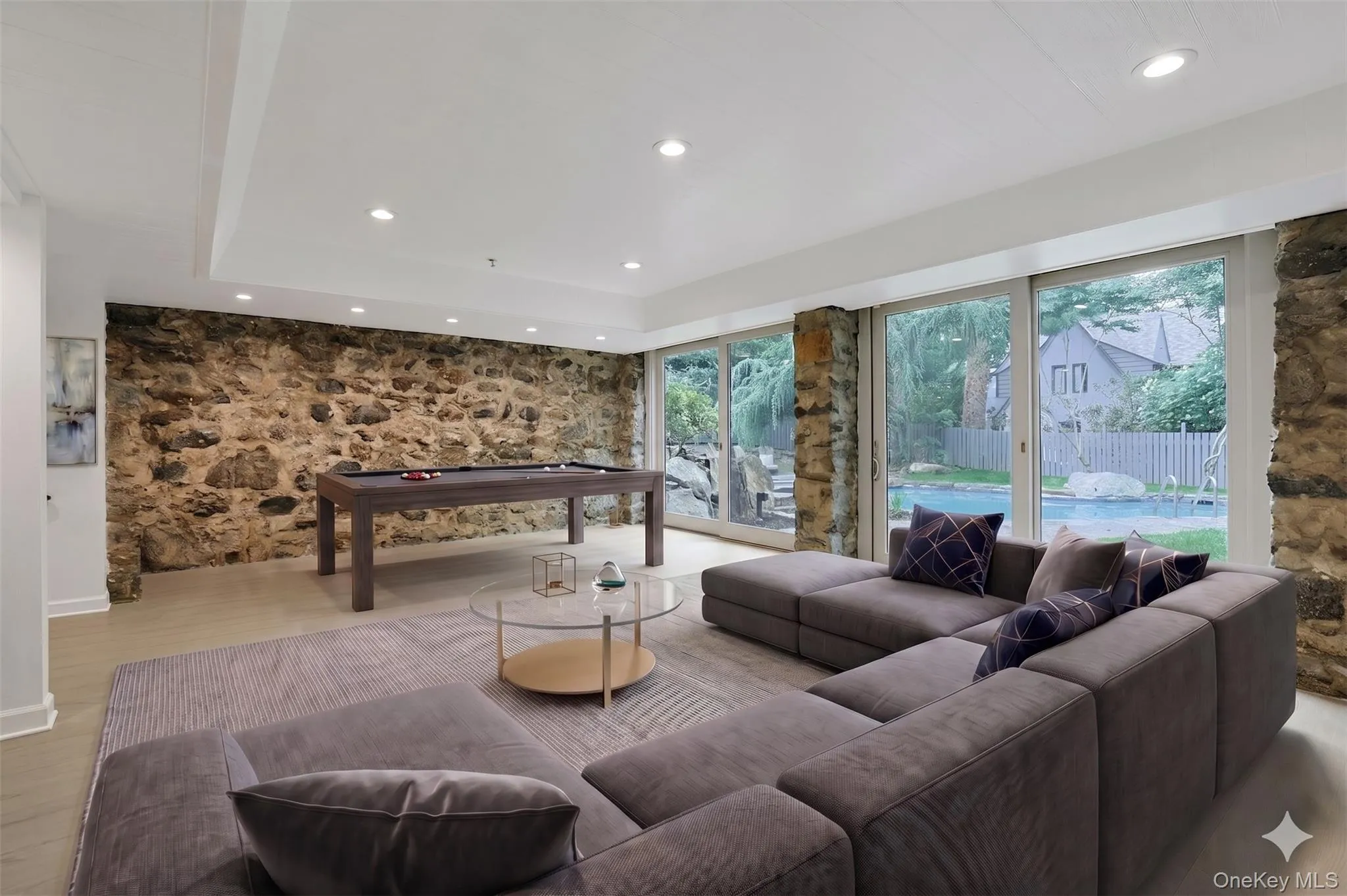 Designed for year-round enjoyment, this remarkable recreation room offers exceptional scale, original stone walls rich with character, and oversized sliding glass doors that blur the line between indoor and outdoor living. (Virtually Staged) Designed for year-round enjoyment, this remarkable recreation room offers exceptional scale, original stone walls rich with character, and oversized sliding glass doors that blur the line between indoor and outdoor living. (Virtually Staged)