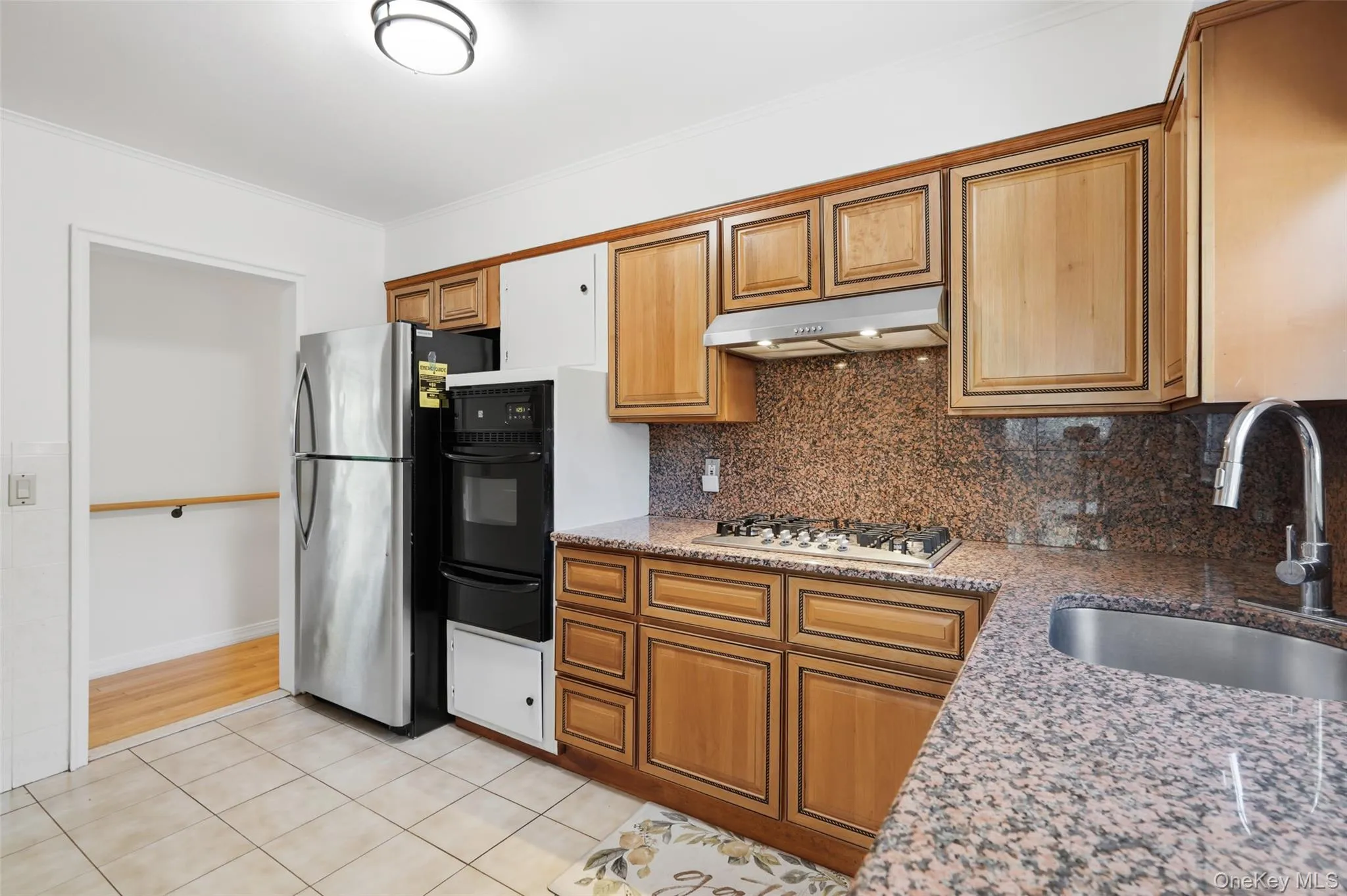 Kitchen featuring granite countertops and backsplash, wood cabinetry, stainless steel gas range, and an undermount sink with a gooseneck faucet Kitchen featuring granite countertops and backsplash, wood cabinetry, stainless steel gas range, and an undermount sink with a gooseneck faucet