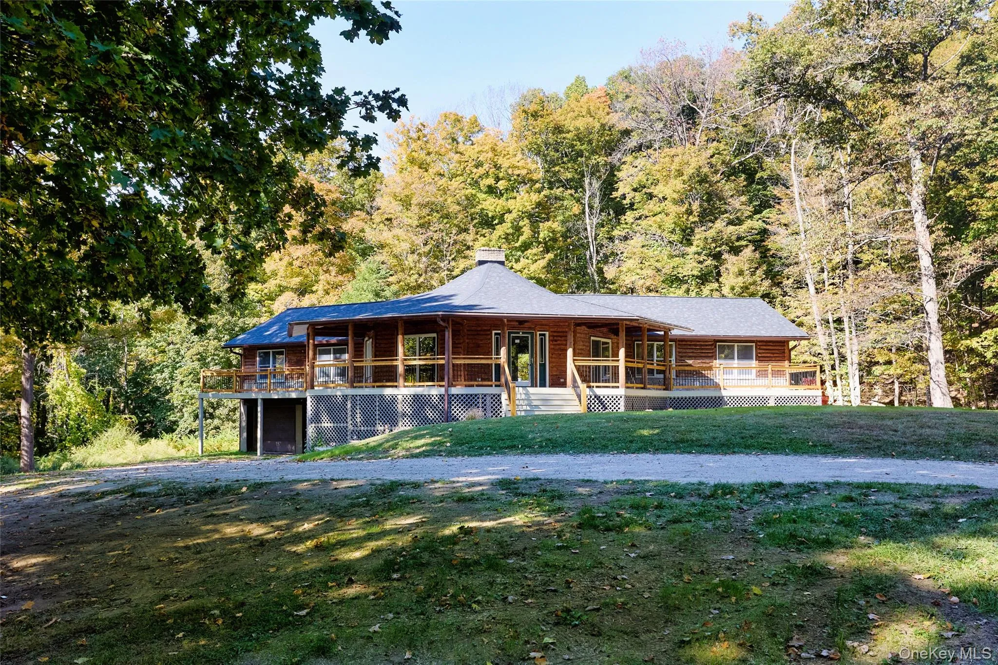 Log-style house featuring a chimney, a front lawn, covered porch, and a forest view Log-style house featuring a chimney, a front lawn, covered porch, and a forest view