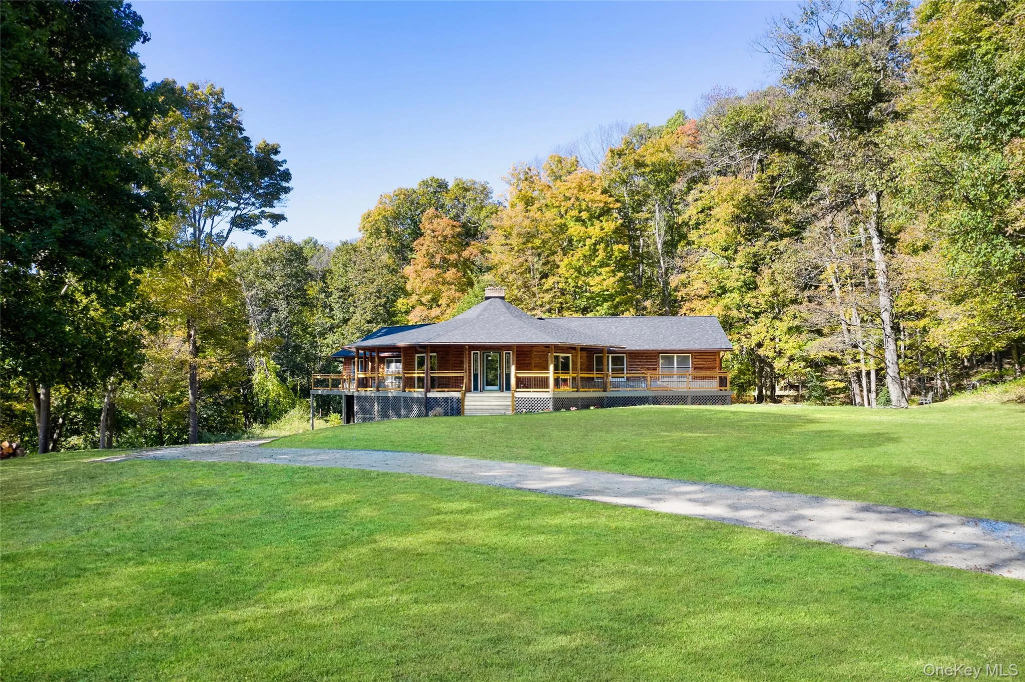 View of front facade featuring a porch, a front yard, a chimney, and a wooded view View of front facade featuring a porch, a front yard, a chimney, and a wooded view