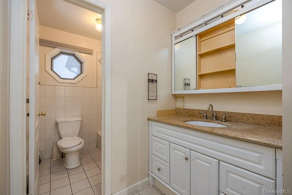 Bathroom featuring vanity, tile walls, light tile patterned flooring, and shower / tub combo Bathroom featuring vanity, tile walls, light tile patterned flooring, and shower / tub combo