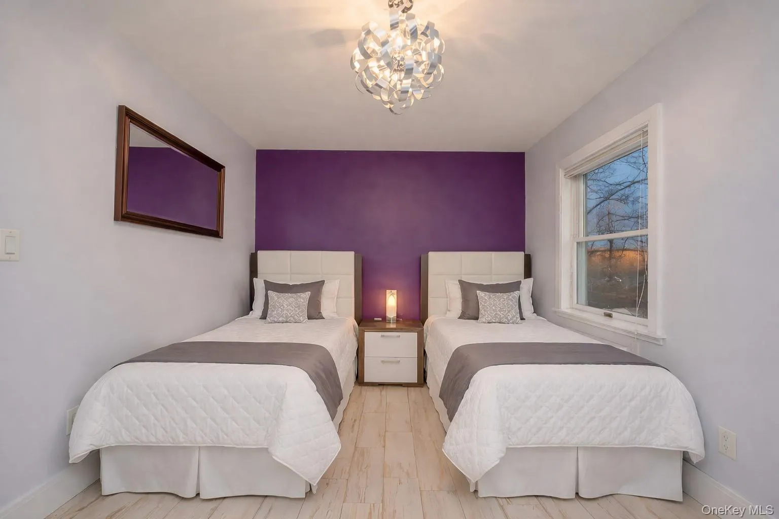 Bedroom featuring an accent wall, a chandelier, and light wood-style flooring Bedroom featuring an accent wall, a chandelier, and light wood-style flooring