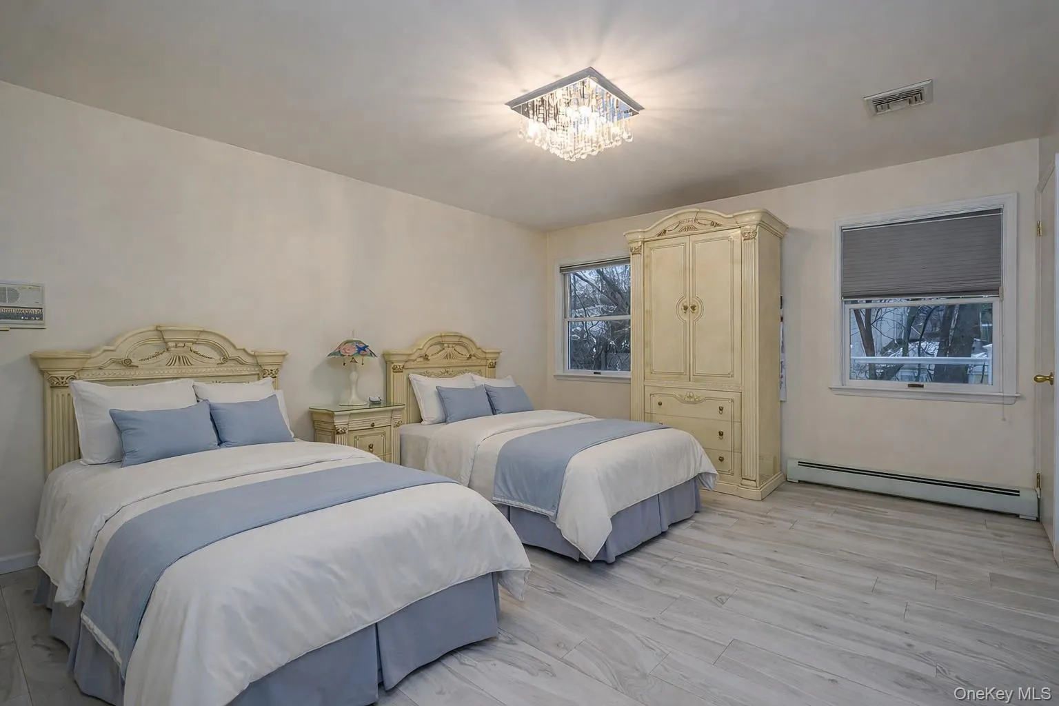 Bedroom featuring baseboard heating, light wood-type flooring, and a chandelier Bedroom featuring baseboard heating, light wood-type flooring, and a chandelier
