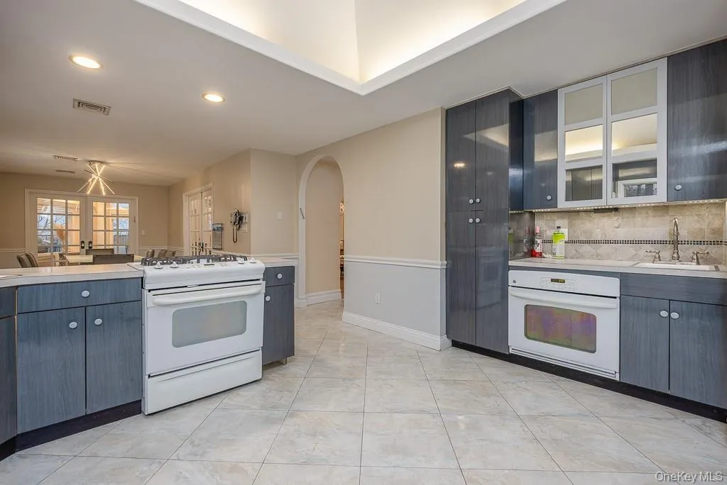 Kitchen featuring white appliances, light countertops, gray cabinets, arched walkways, and recessed lighting Kitchen featuring white appliances, light countertops, gray cabinets, arched walkways, and recessed lighting