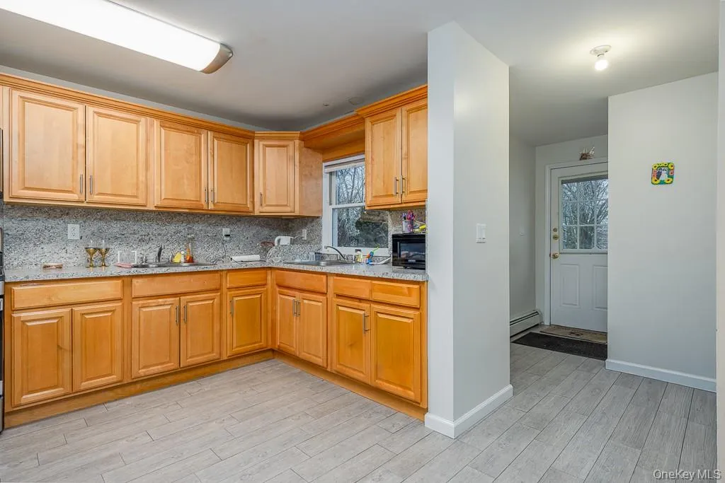 Kitchen featuring light wood-type flooring, backsplash, and light stone counters Kitchen featuring light wood-type flooring, backsplash, and light stone counters