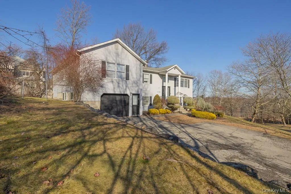 View of side of home featuring a garage, driveway, and a yard View of side of home featuring a garage, driveway, and a yard